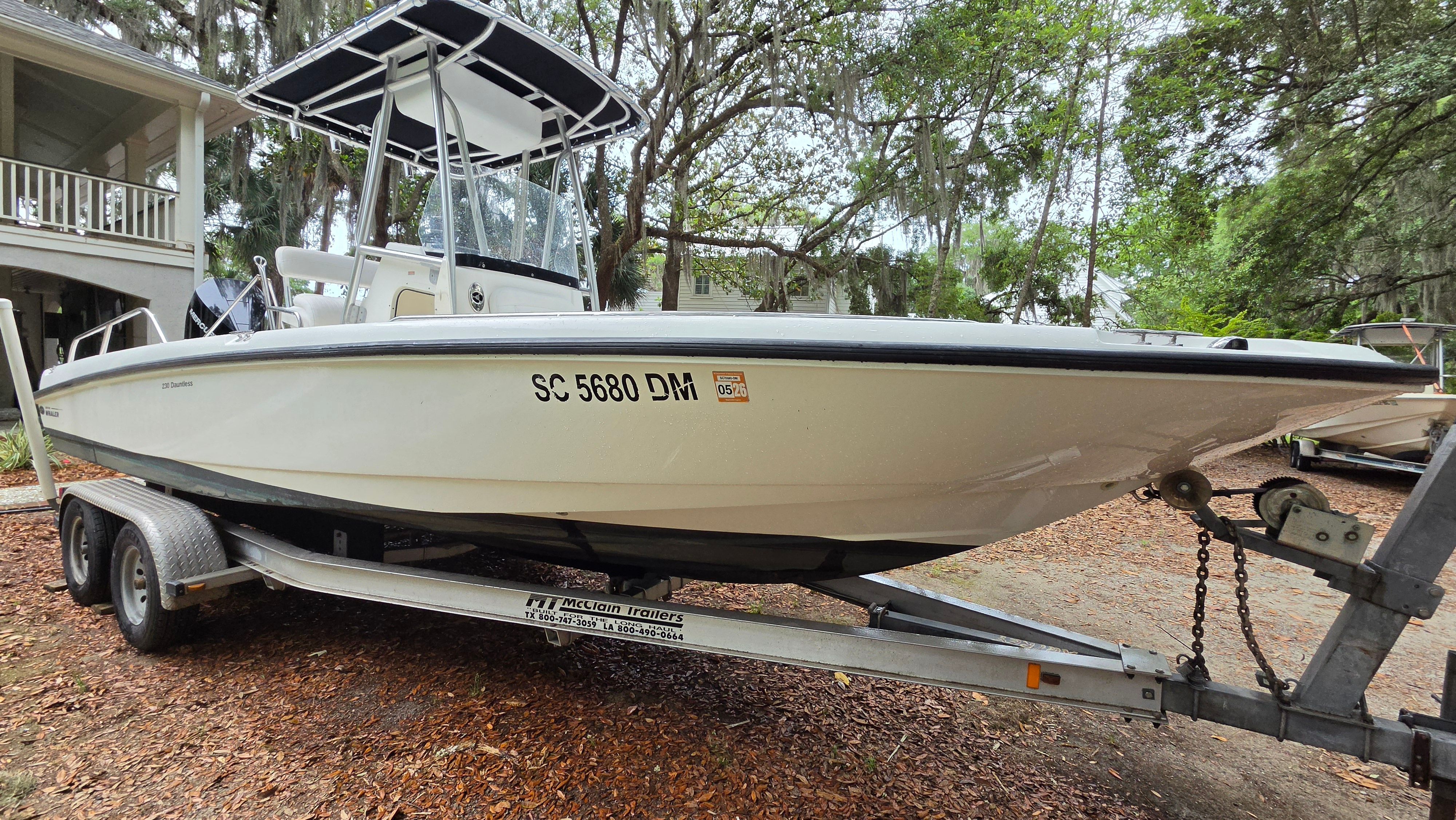 A 2008 Boston Whaler 230 Dauntless on a trailer, surrounded by trees.