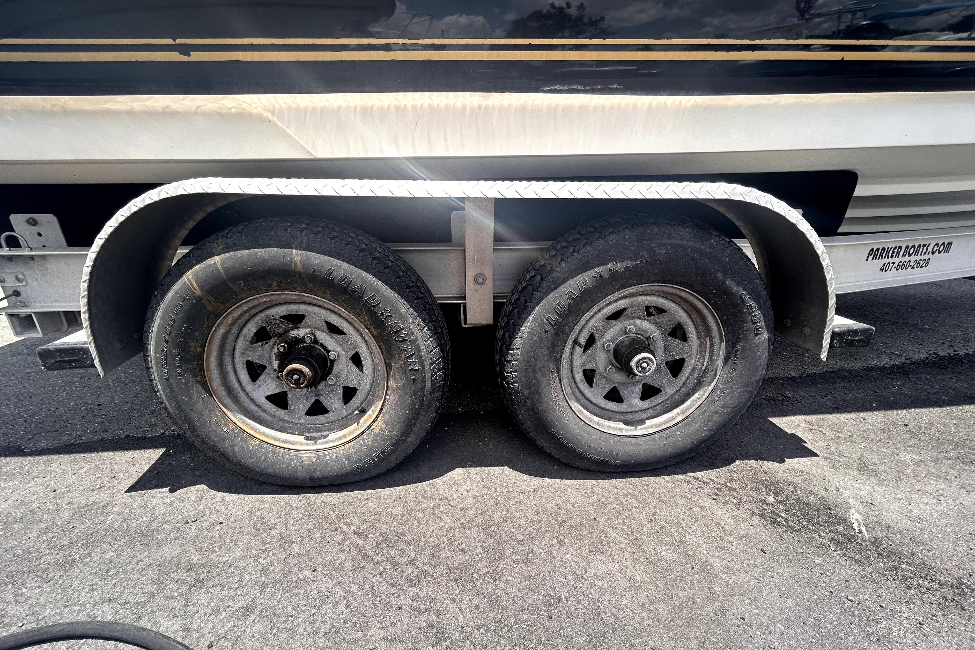 Trailer wheels of a 2006 Sea Ray 250 Amberjack boat on asphalt.