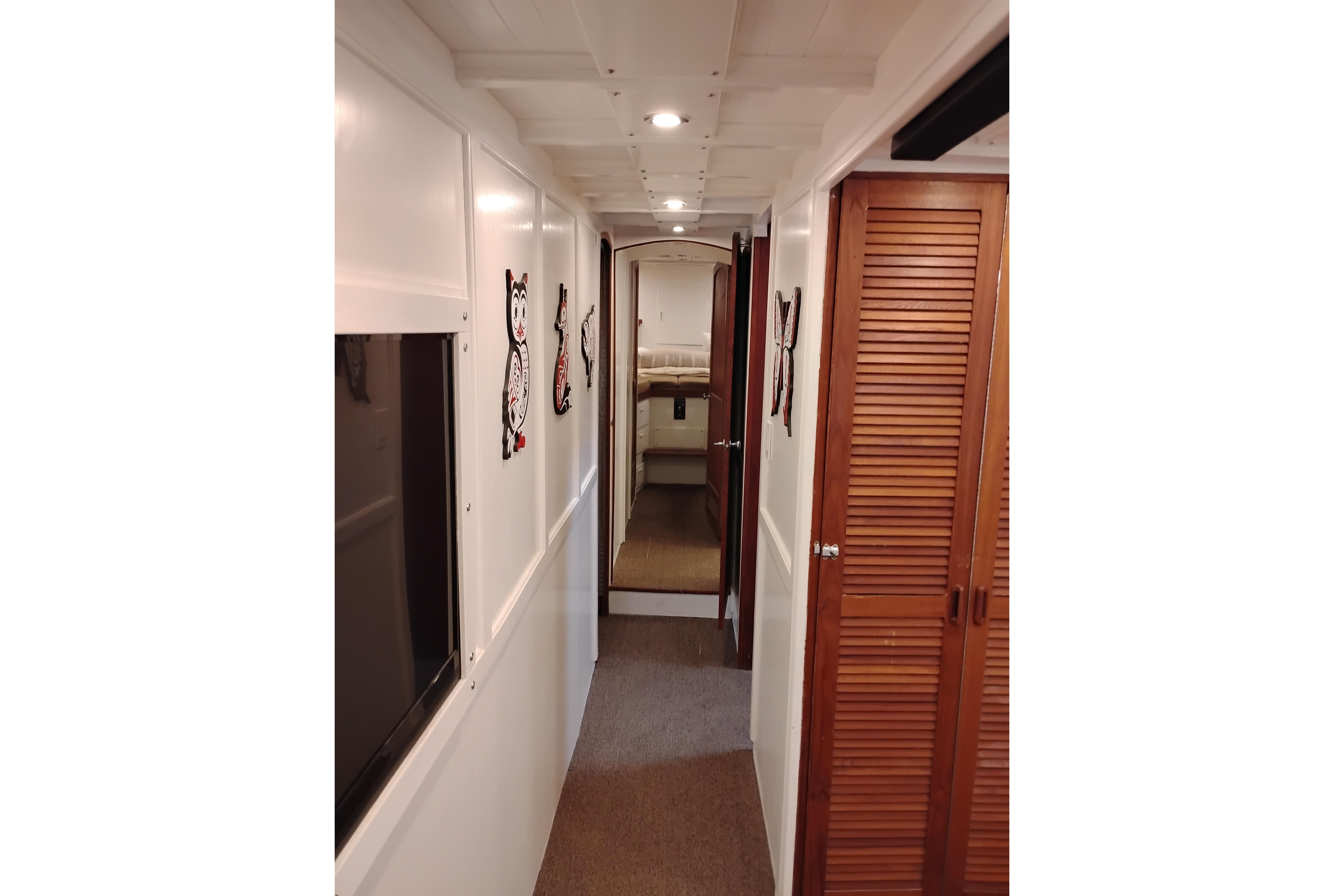 Narrow hallway inside 1977 Custom International Offshore 65 yacht, featuring wooden doors and wall decor.