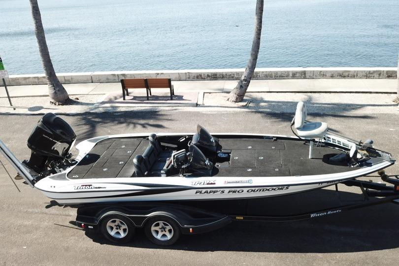 2005 Triton Tr-21X PD boat on trailer by waterfront, palm trees in background.