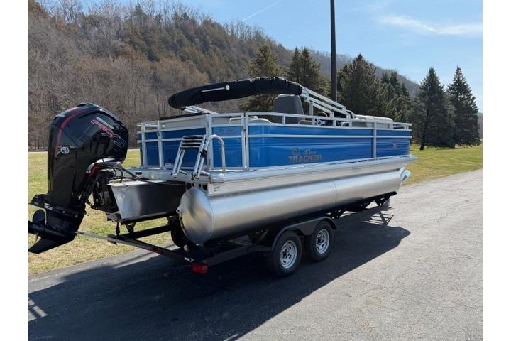 2026 Sun Tracker Fishin' Barge 20 DLX pontoon boat on trailer, parked outdoors.