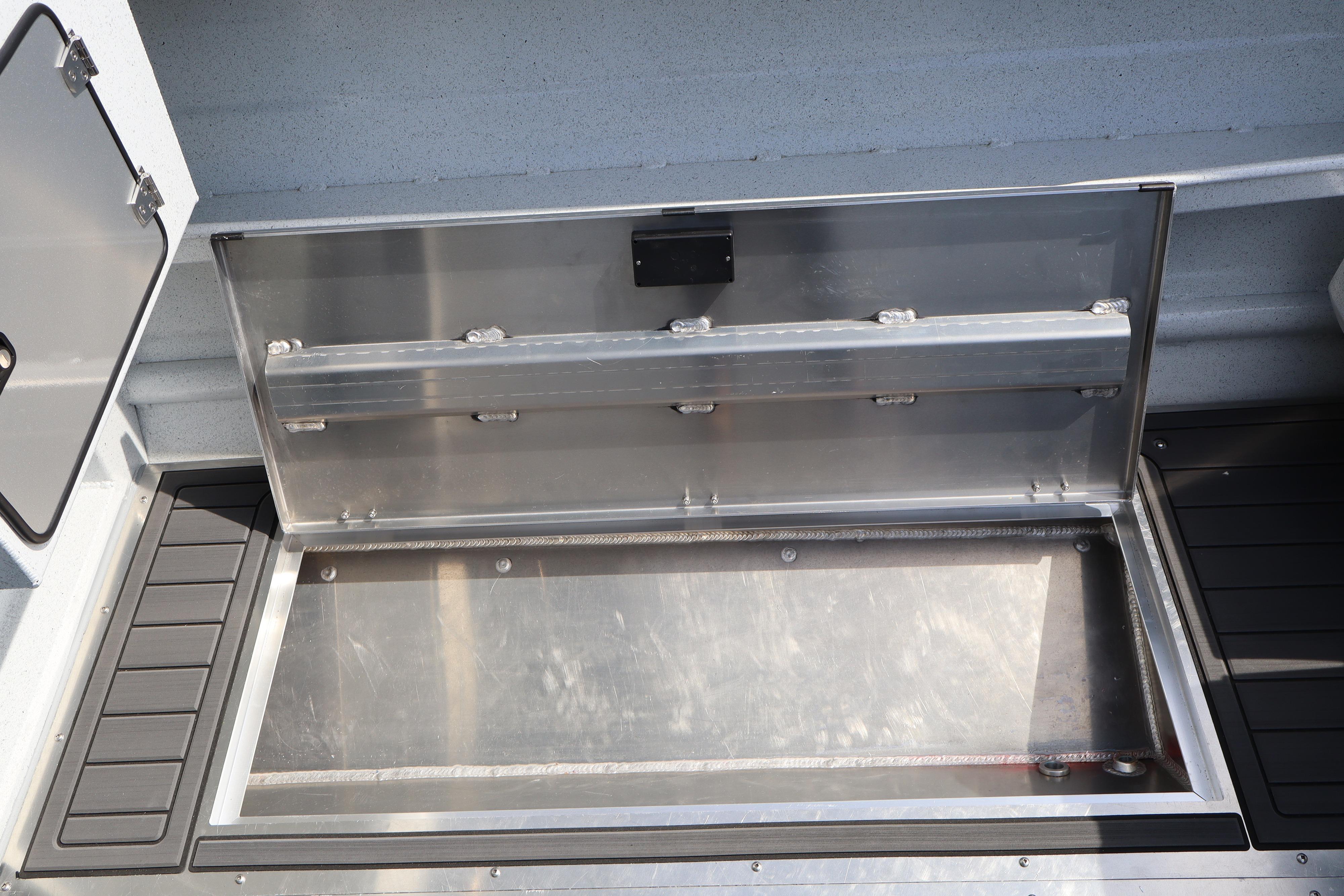 Open storage compartment on 2026 KingFisher 25 XAC boat, showcasing sleek metal design.