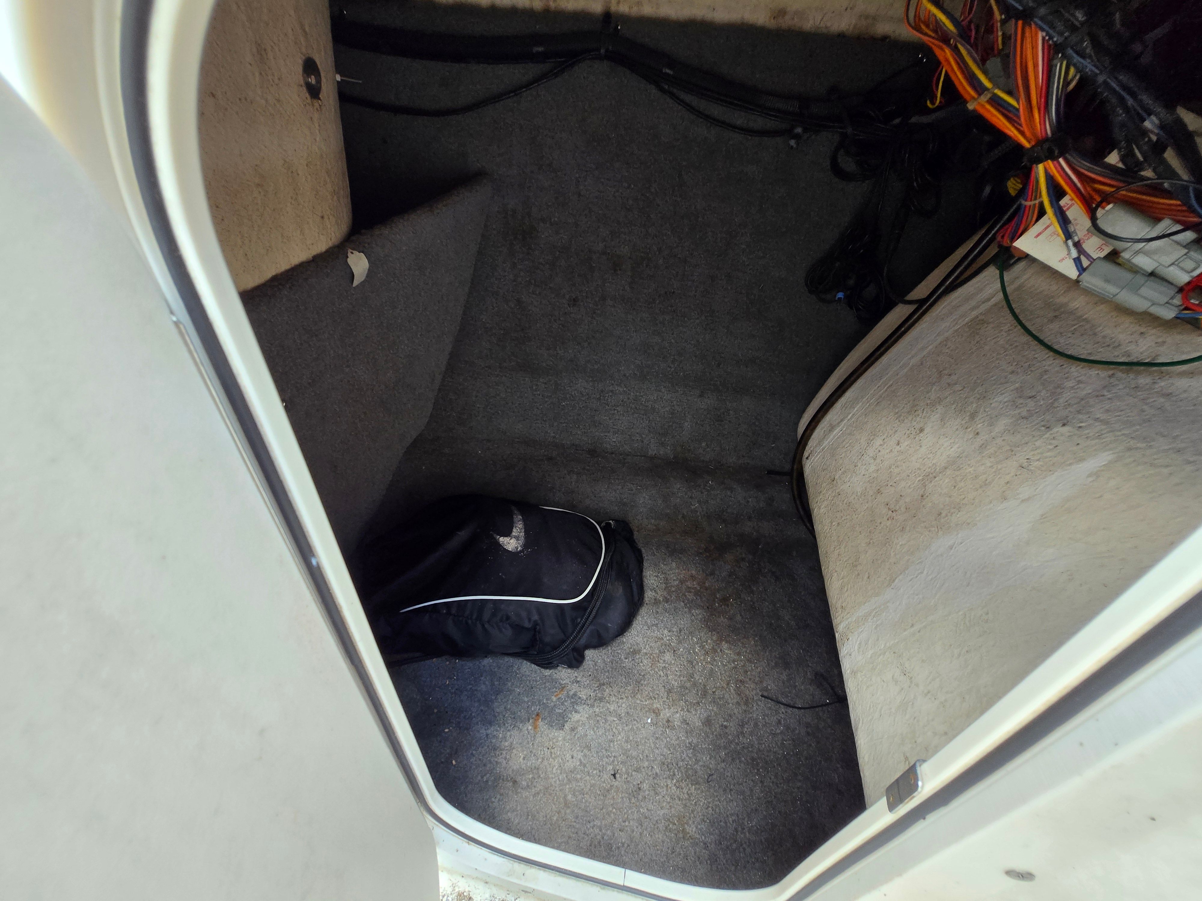 An interior space with carpeted floor and a black bag in the corner.