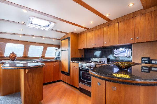 Luxurious kitchen interior of 2025 Shuttleworth 52 AeroRig yacht with wood cabinetry and modern appliances.