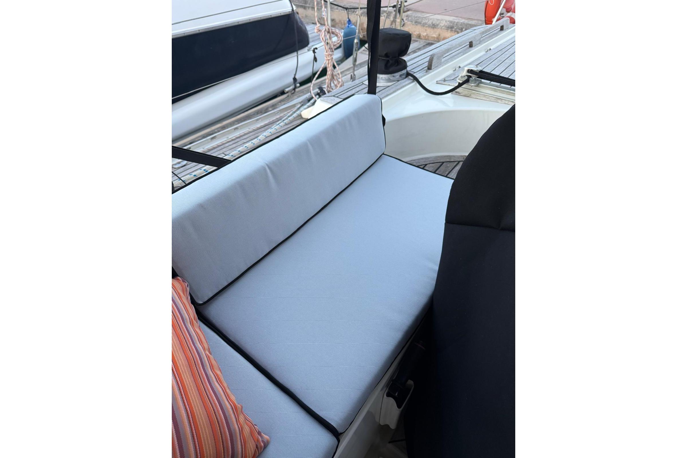 Cushioned seating area on 1985 Oyster 435 yacht deck with striped pillow.