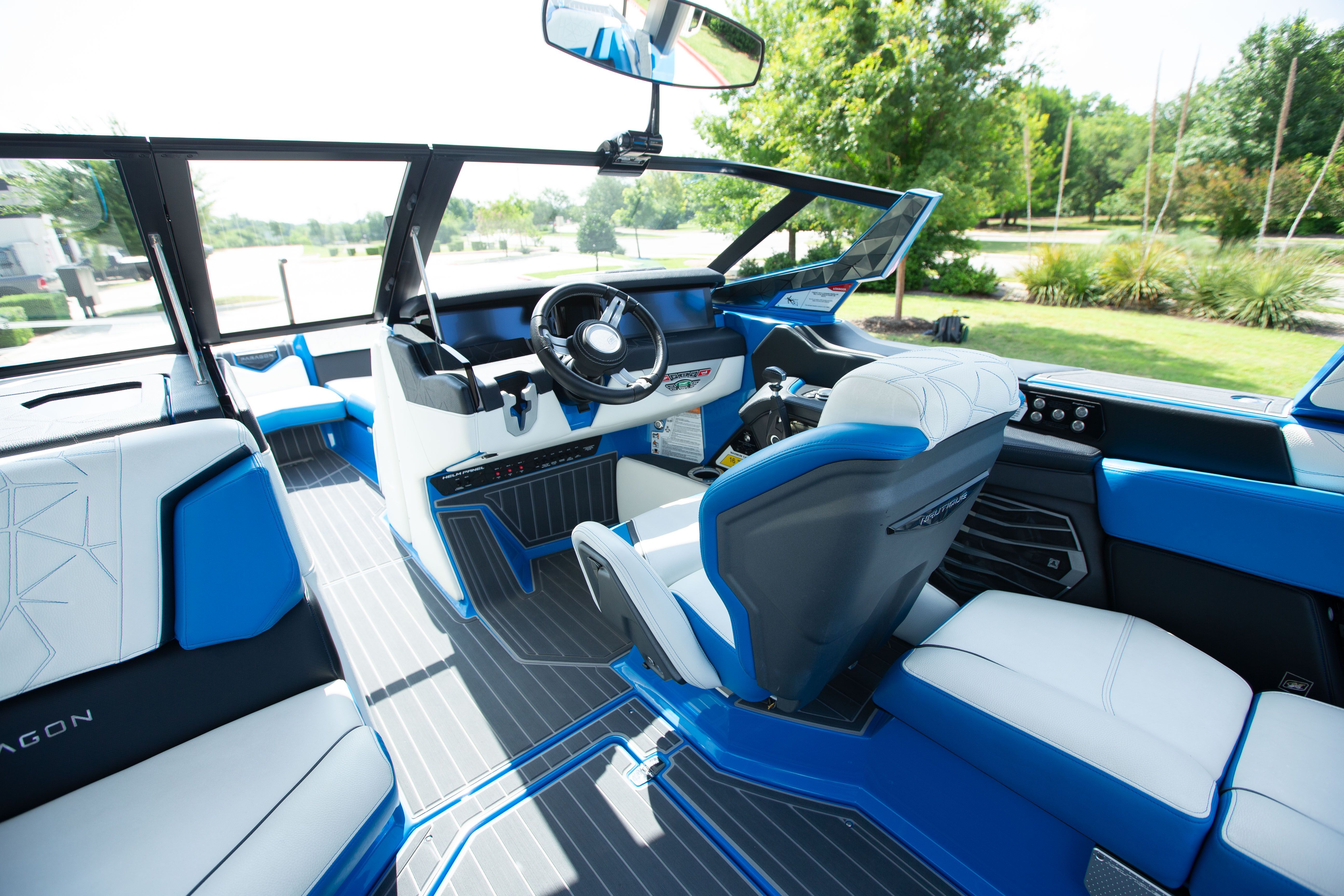 The interior of a modern boat with blue and white seats and a steering console.