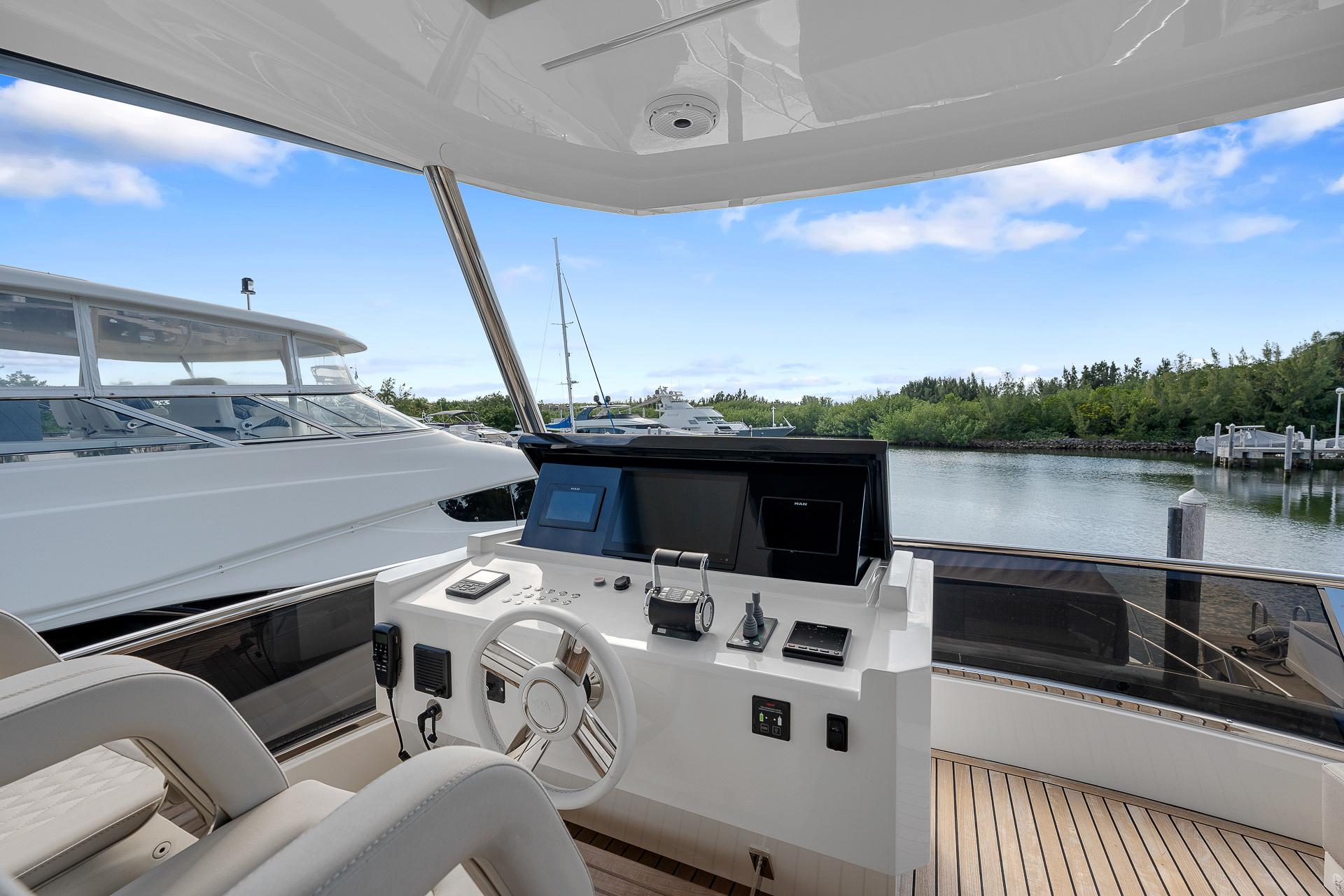 Astondoa 66 yacht helm, 2022 model, with modern controls and scenic marina view.