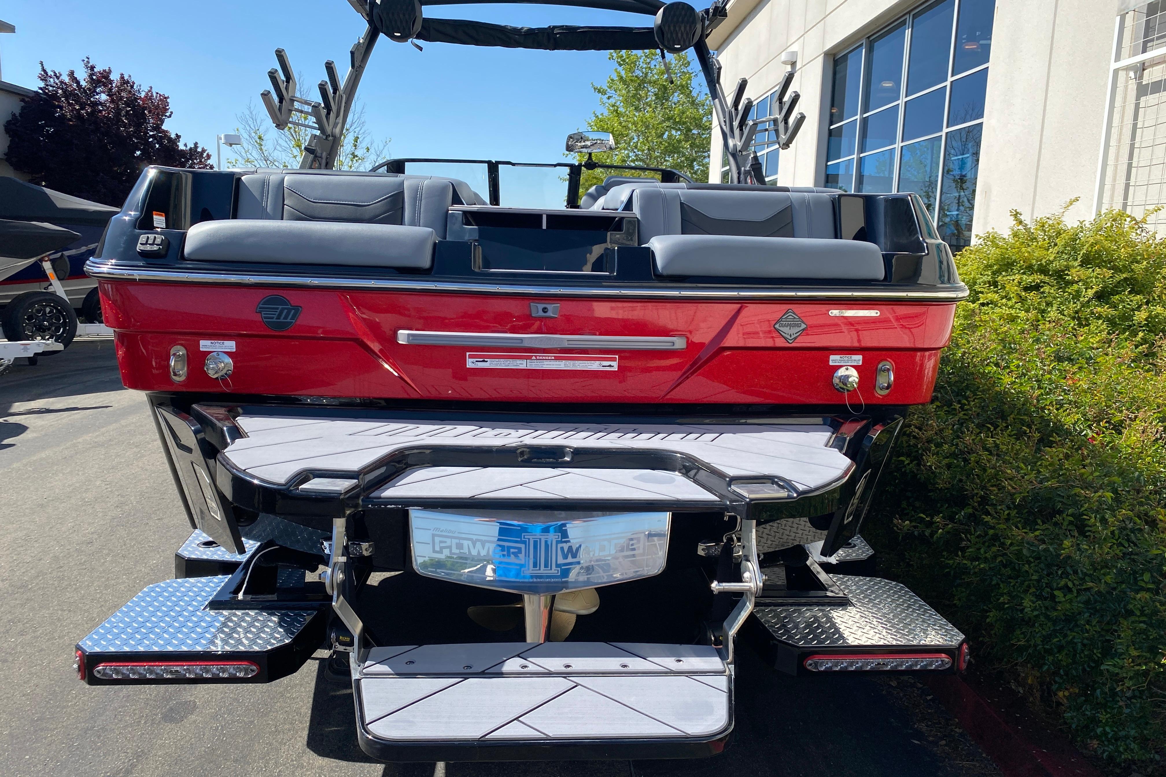 2025 Malibu Wakesetter 23 LSV boat, red exterior, rear view, parked outdoors.