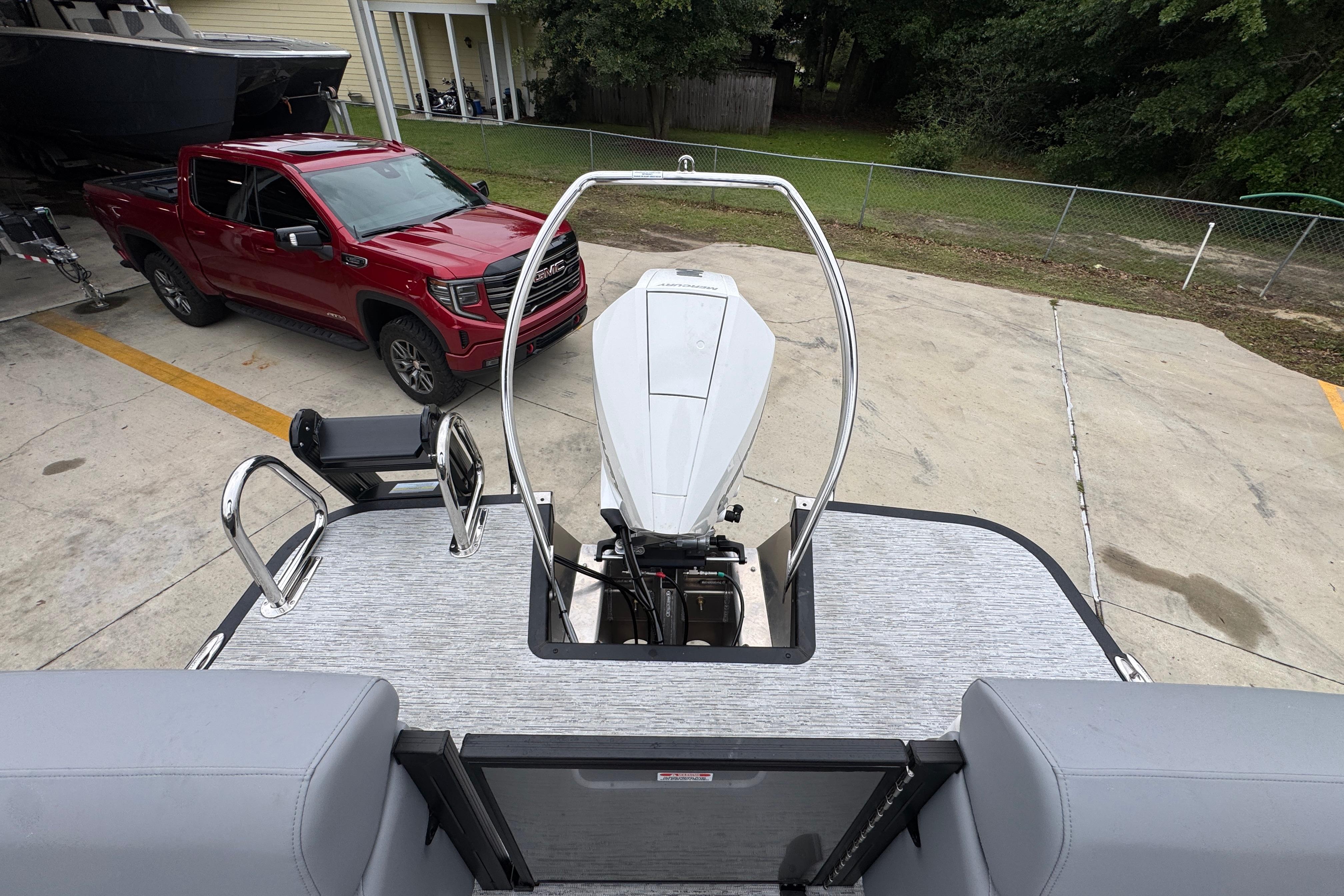 2027 Bennington 24 MFB boat with outboard motor, parked near a red pickup truck.