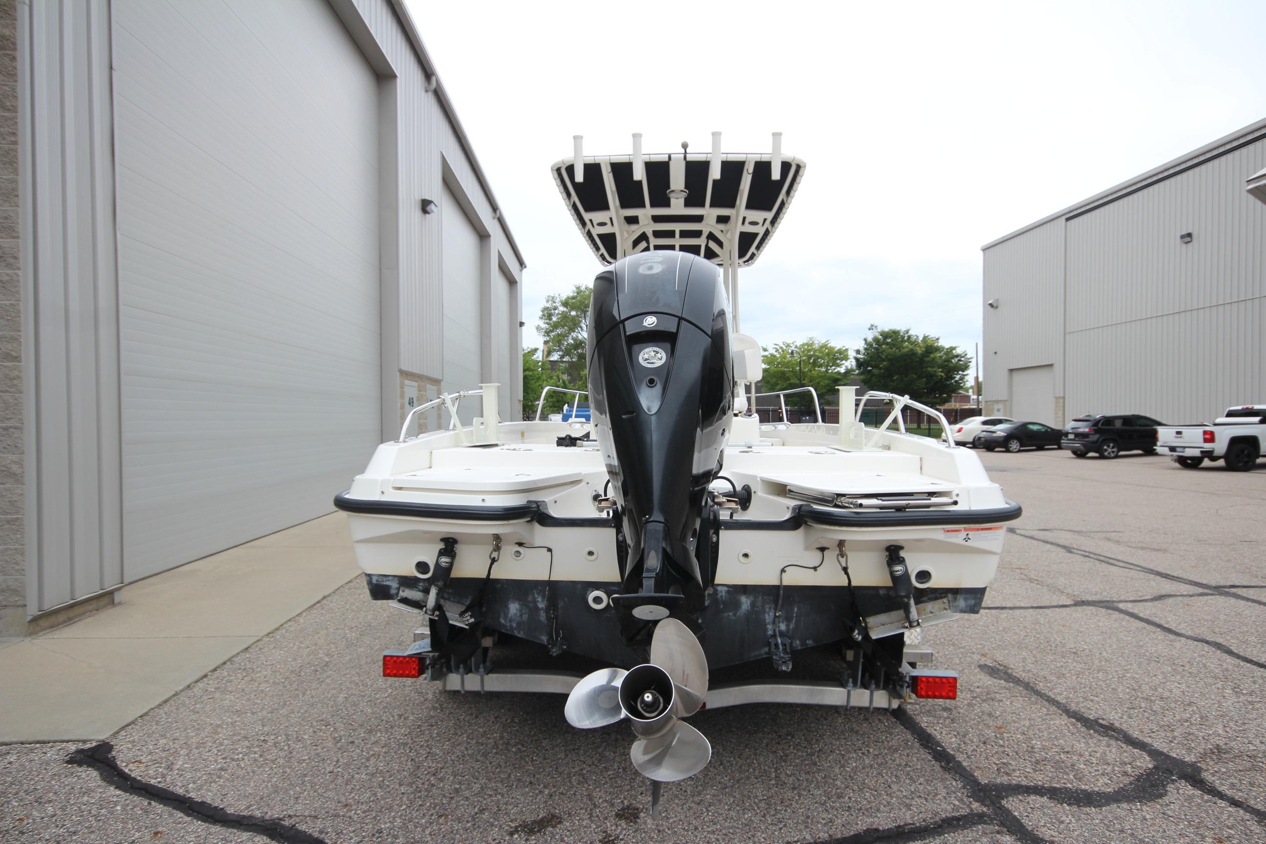 2014 Boston Whaler 210 Dauntless boat with outboard motor, parked near industrial buildings.