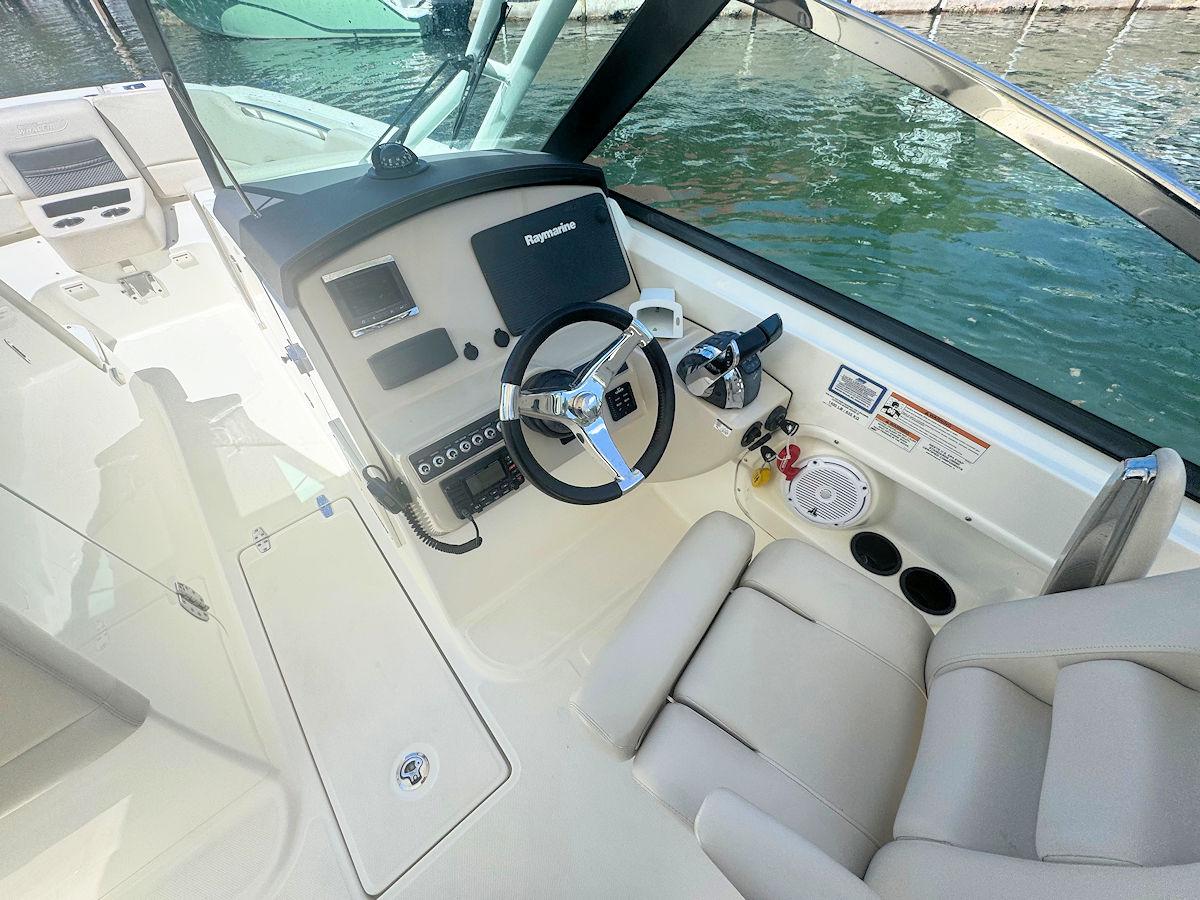 2016 Boston Whaler 270 Vantage helm with steering wheel and controls, docked by water.