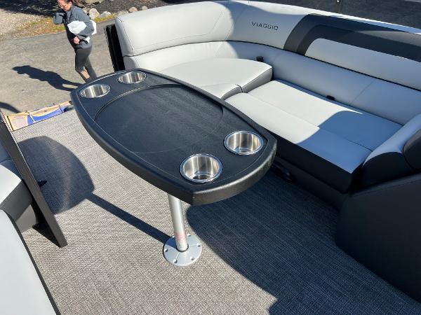 The image shows the interior of a Viaggio Lago 22U Tri Toon boat with a table and seating.