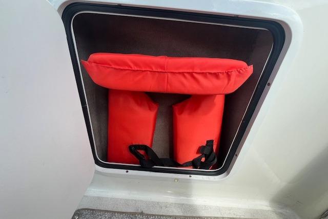 Red life jackets stored in a compartment on a 2003 Sea Ray 260 Sundancer boat.