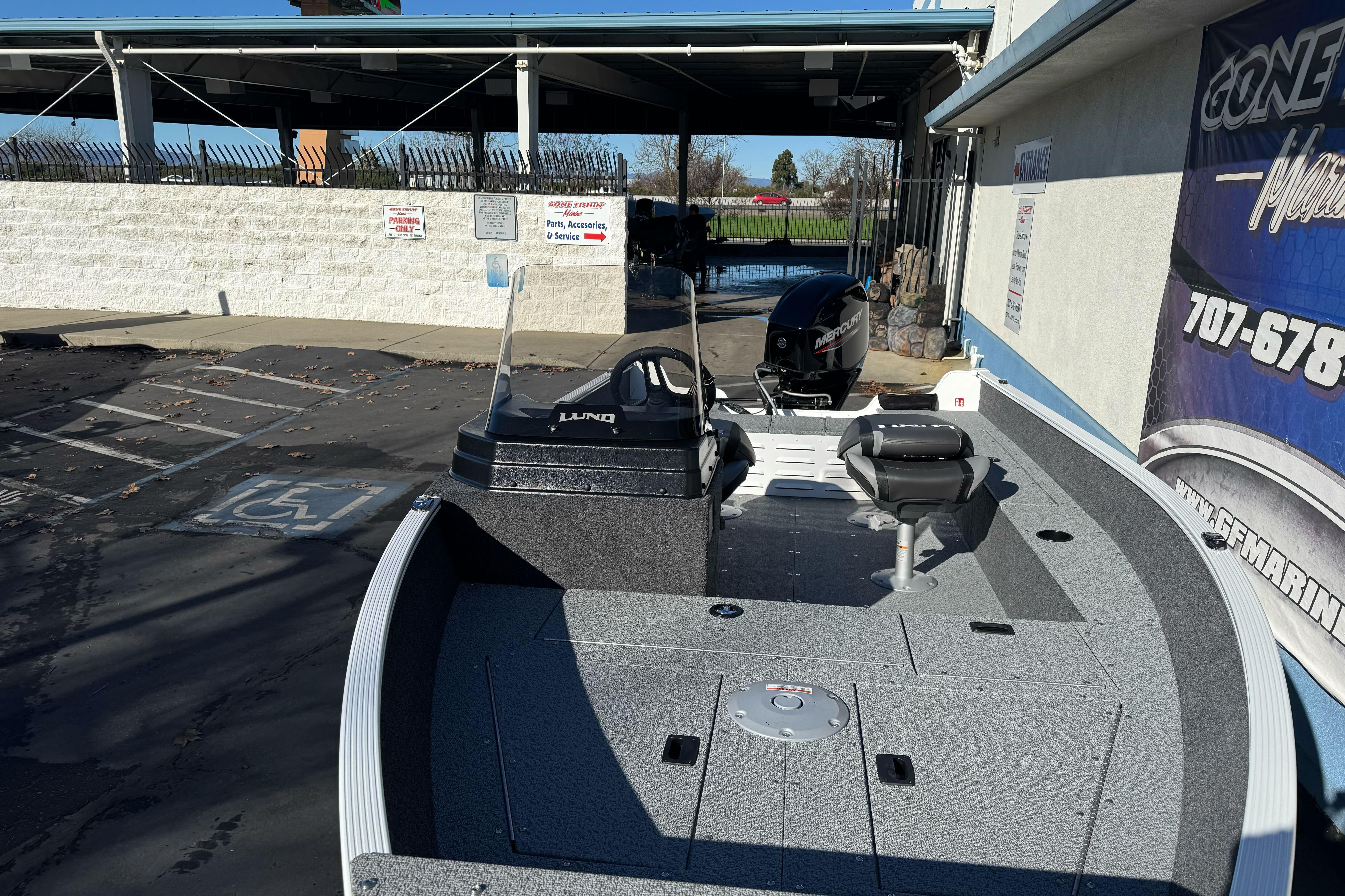 2026 Lund 1650 Angler SS fishing boat with Mercury engine, parked outdoors.