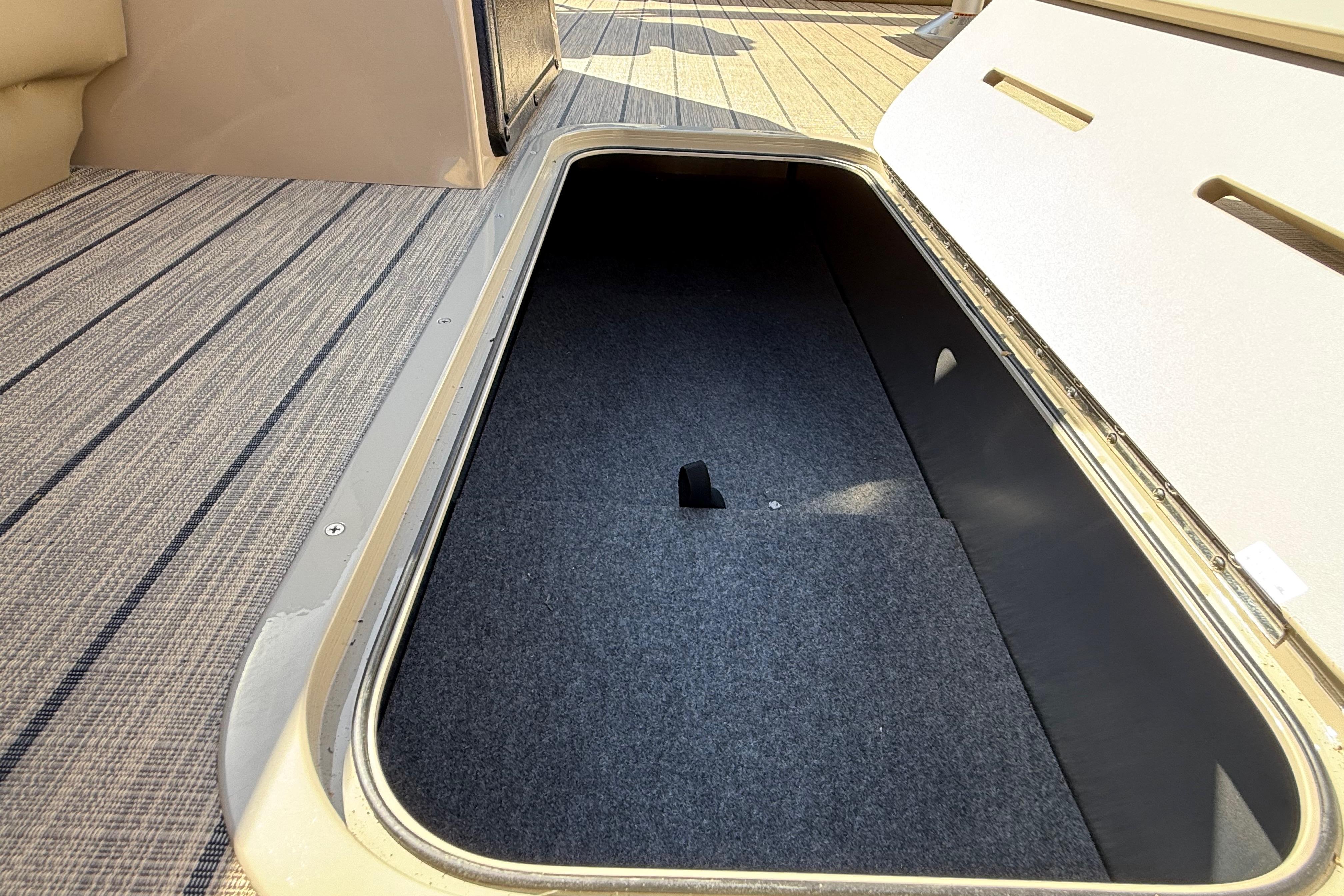 Storage compartment of 2026 SunCatcher Select 322SL boat with carpeted interior.