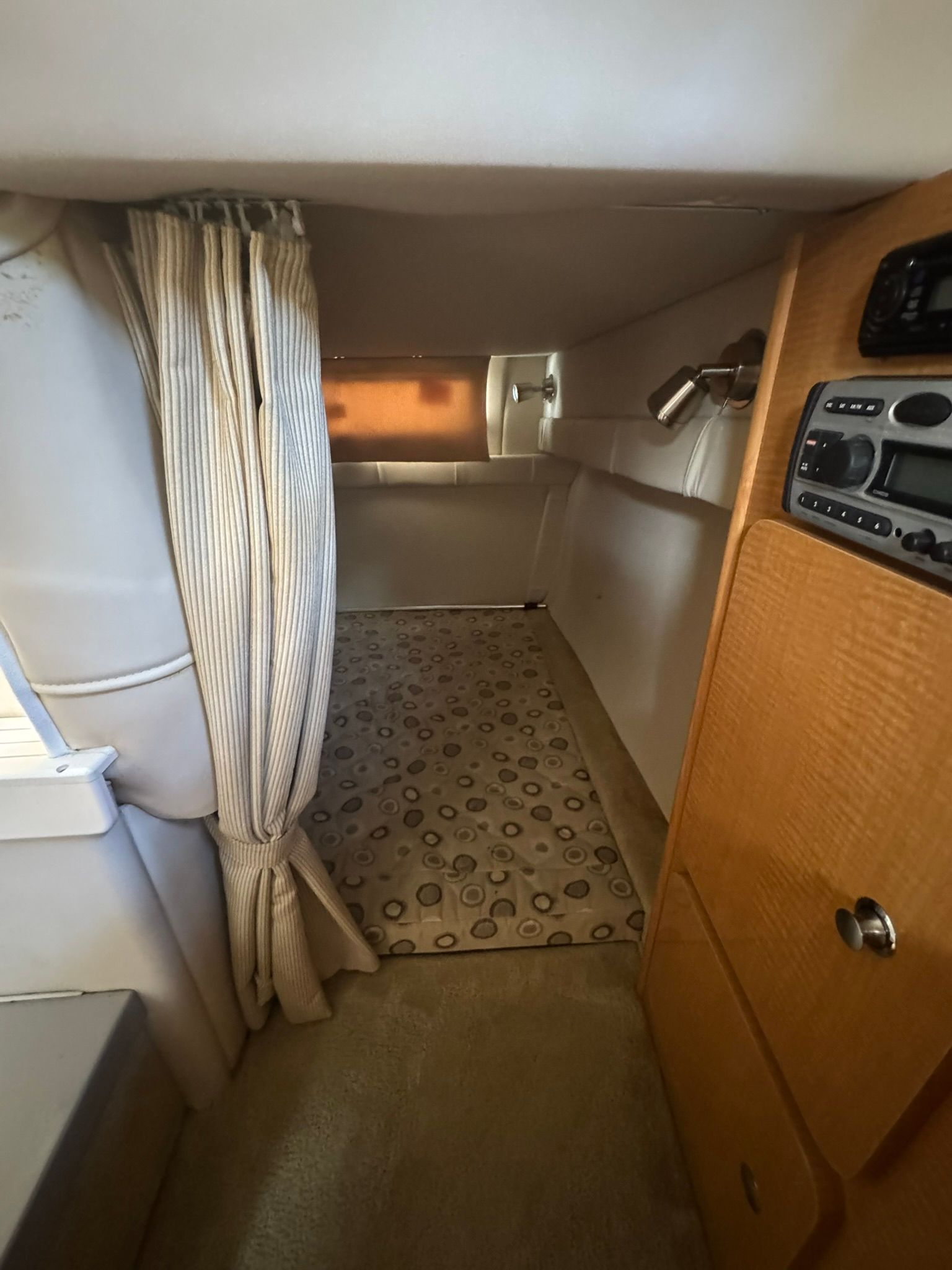 Interior of a cabin with curtain, carpet, and wooden cabinet.