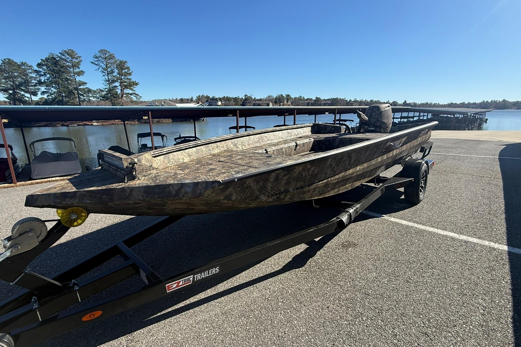 2026 Excel 183 Tomahawk boat on trailer by a lakeside under clear blue sky.