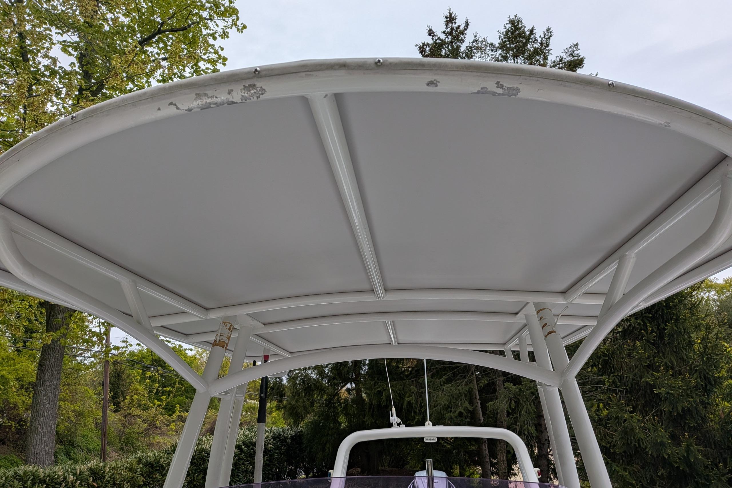 2016 Brig E780 boat canopy with visible wear, surrounded by trees.