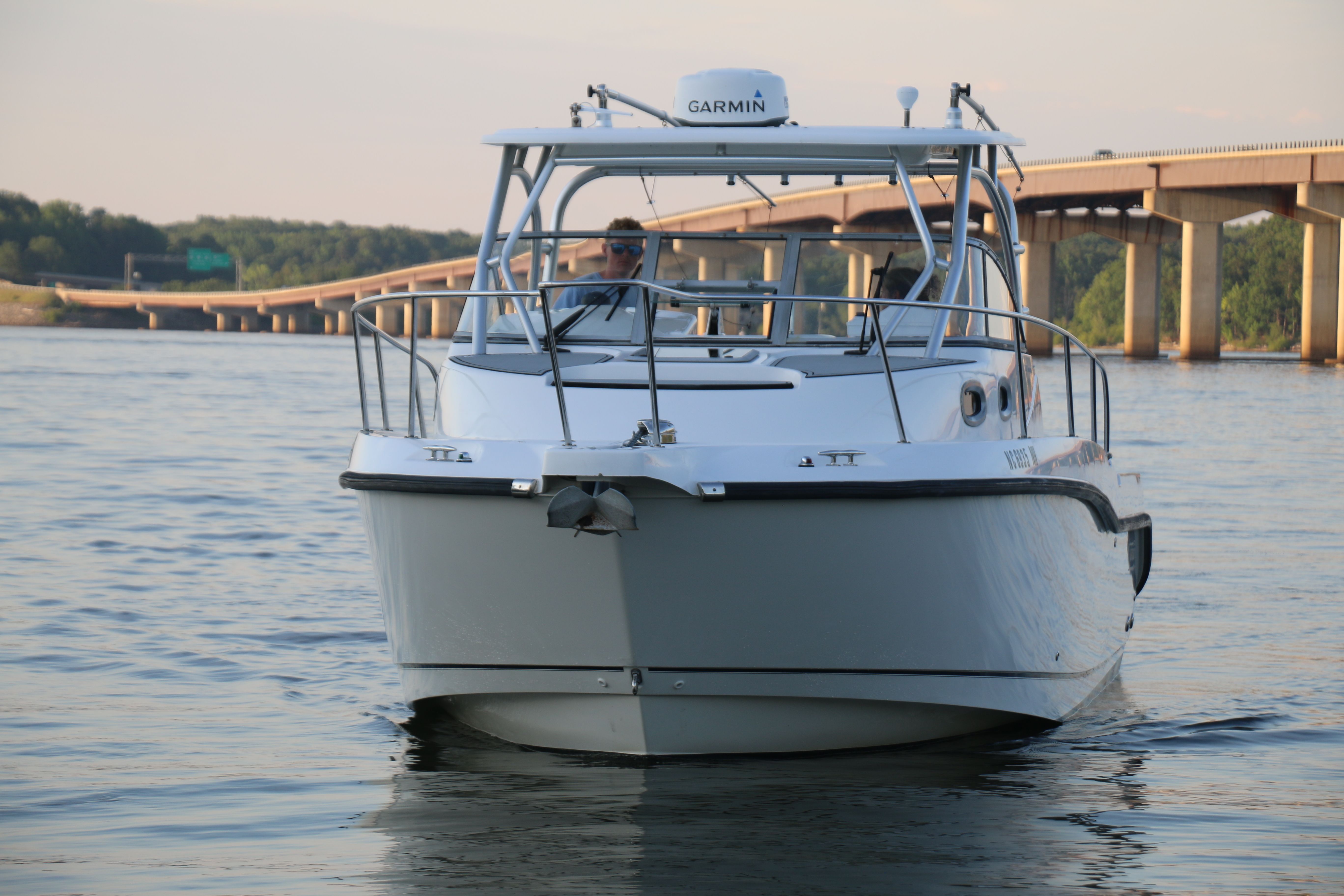 A 2006 Boston Whaler 305 Conquest cruising on calm waters under a bridge.