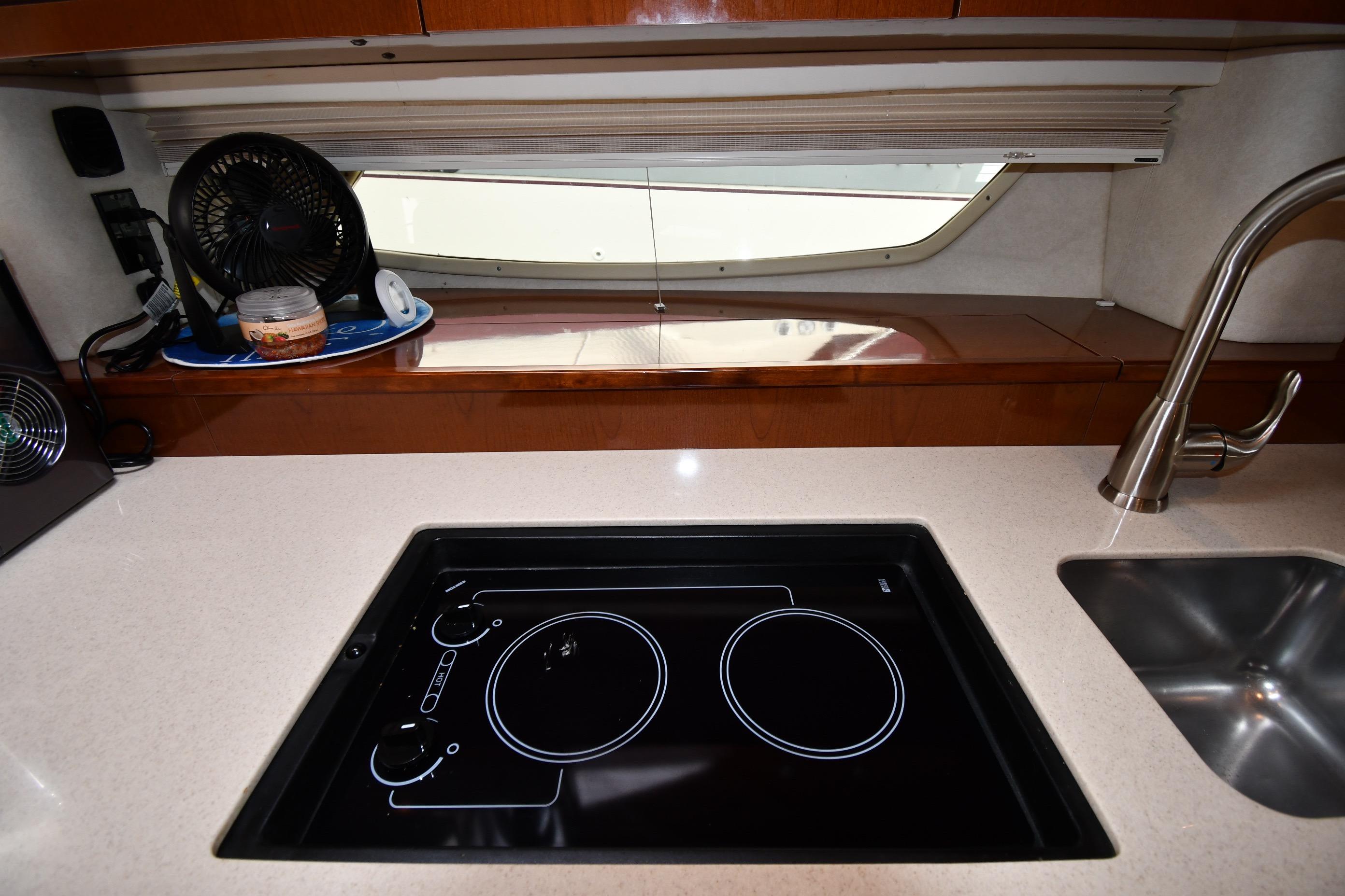 Modern kitchen area in a 2008 Sea Ray Sundancer 350 yacht with stovetop and sink.