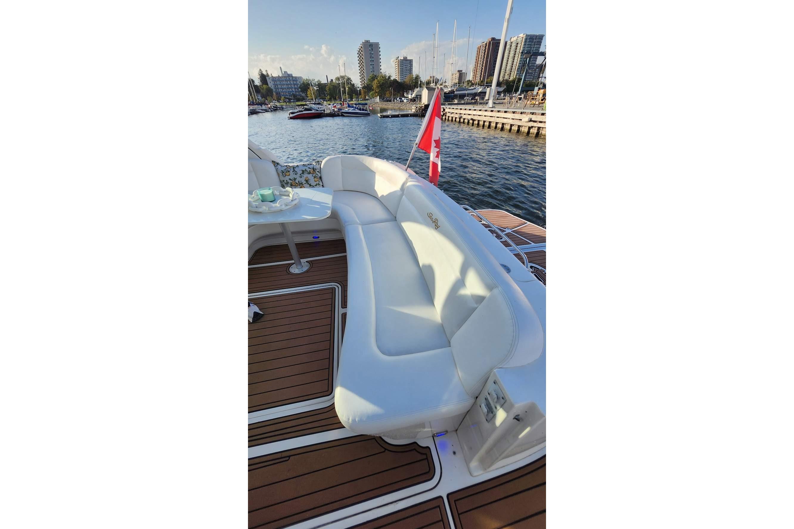 Luxurious 2007 Sea Ray 480 Sundancer yacht with white seating and Canadian flag, docked in marina.