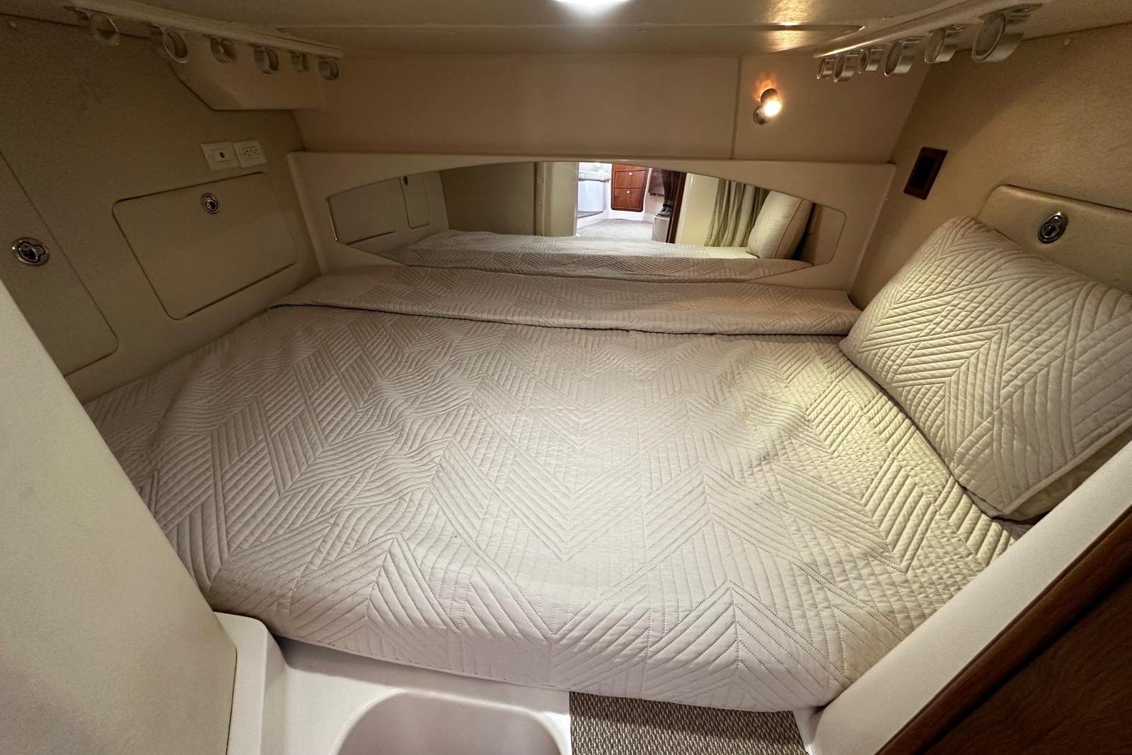 Cozy cabin interior of 2006 Grady-White Express 360 with quilted bedding and soft lighting.