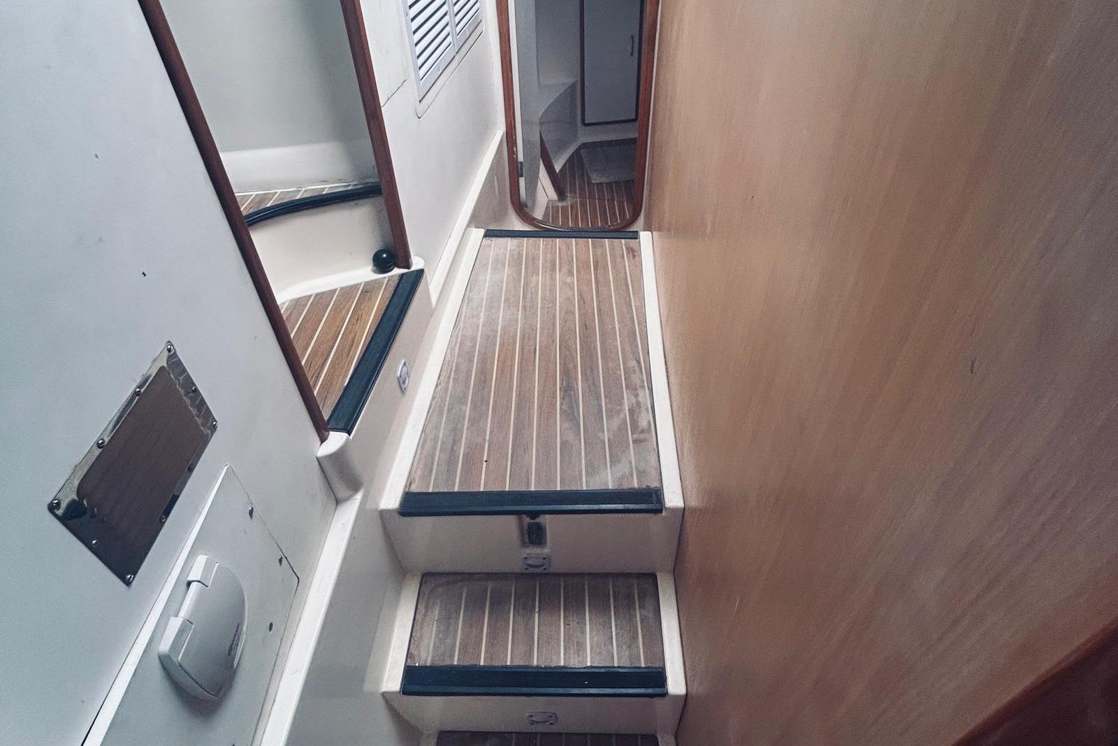 Interior stairs of a 2001 Robertson & Caine Leopard yacht with wooden steps.
