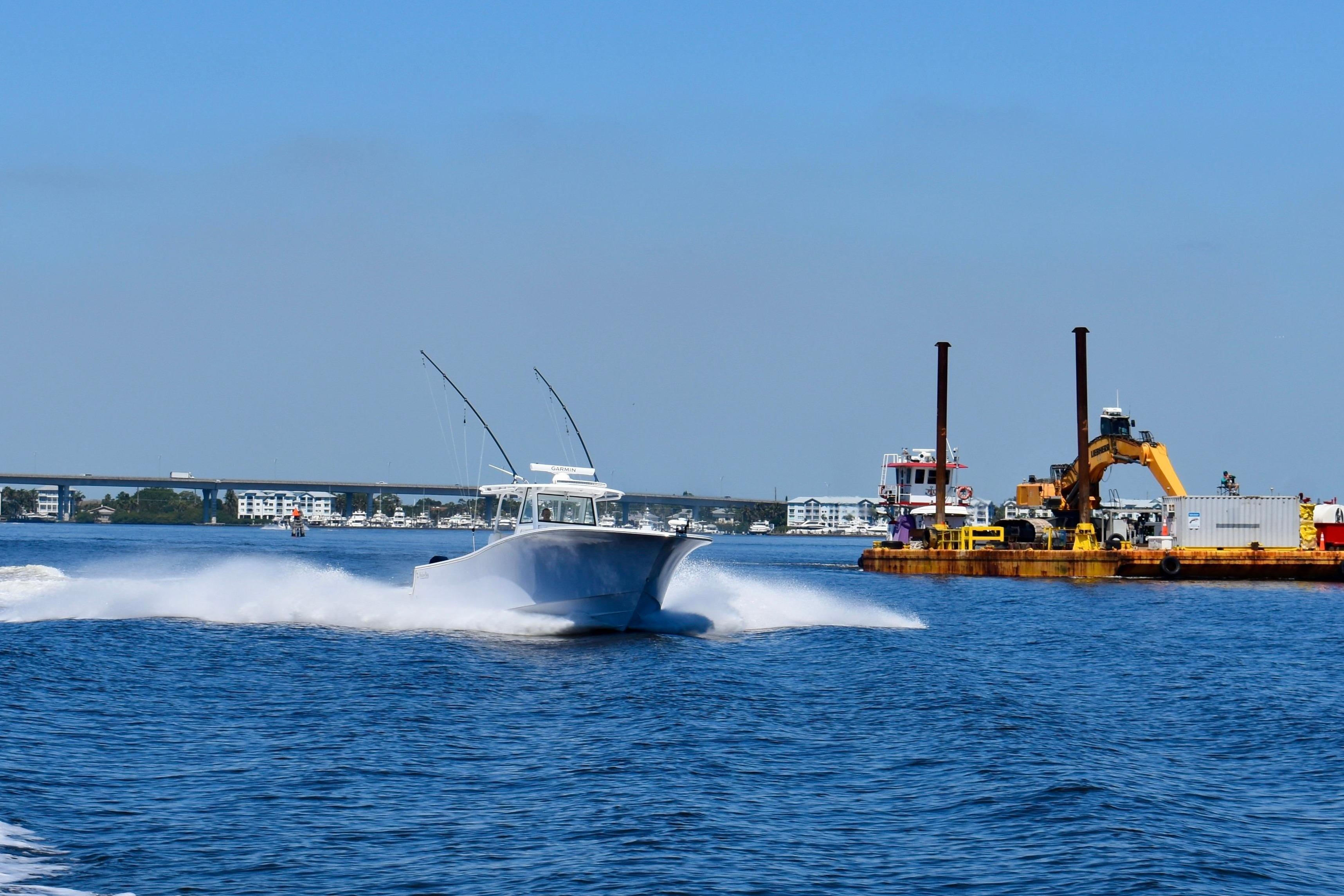 Onslow Bay 41 Tournament boat speeding on water near construction barge, 2022 model.