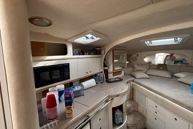 Interior of 2000 Sea Ray Sundancer 310 yacht with kitchenette and cozy sleeping area.