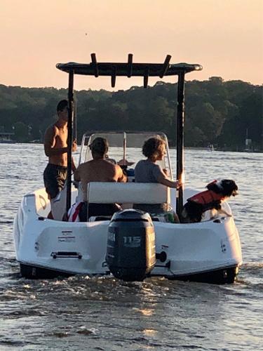 2003 Wellcraft 180 Fisherman boat with passengers and a dog on a lake at sunset.