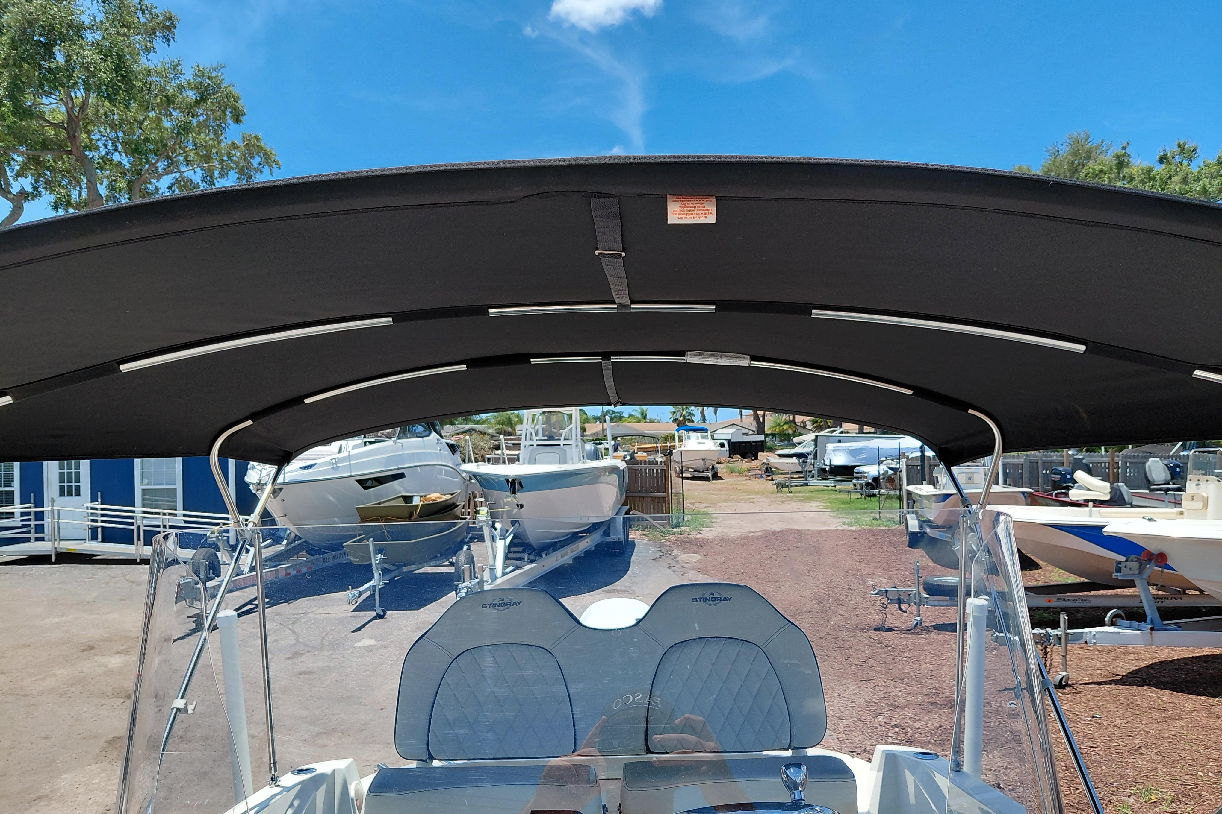 2023 Stingray 206 CC boat with canopy, parked in a marina under clear blue sky.