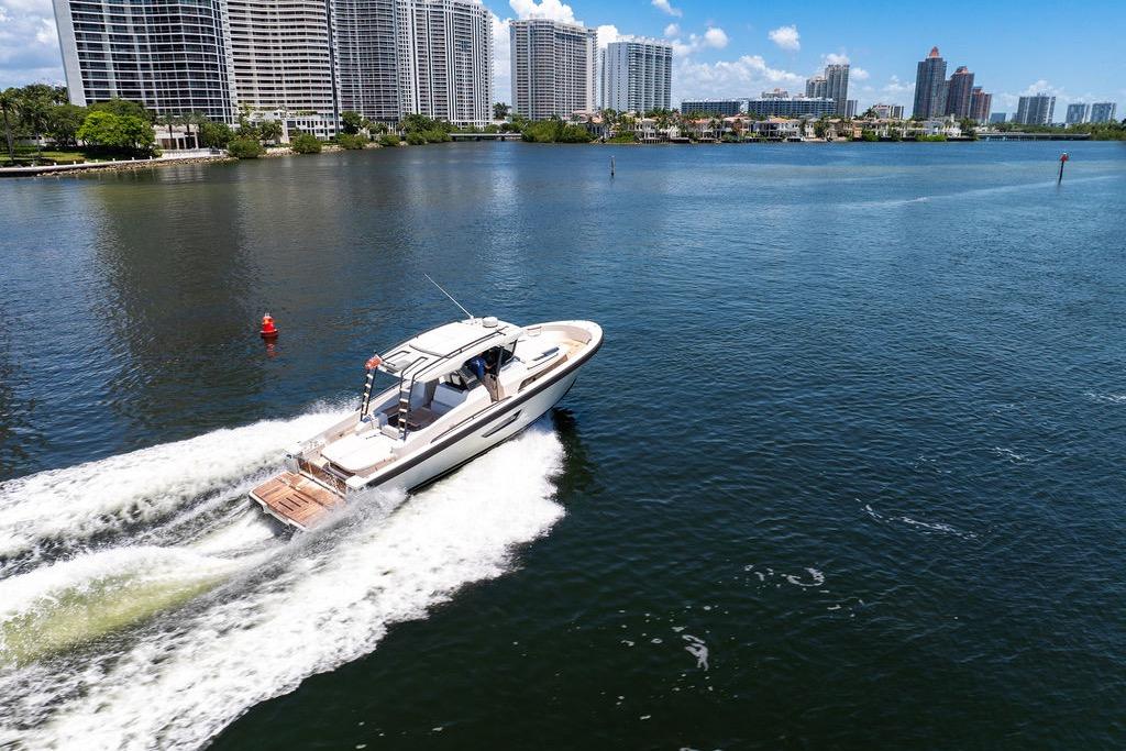 2021 Bluegame BG 42 yacht cruising near city skyline on a sunny day.