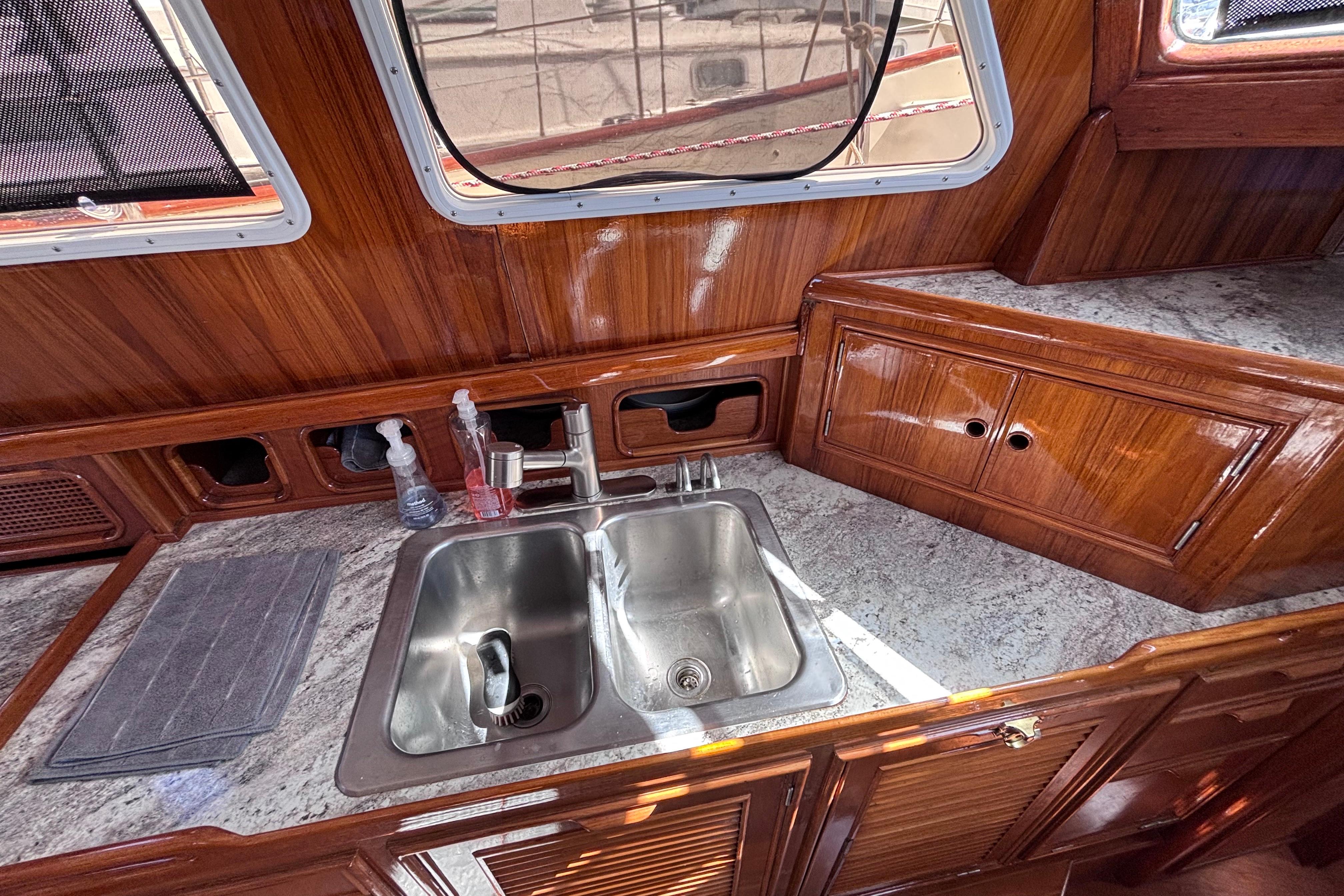 1978 Swift 33 yacht kitchen with wooden cabinets and stainless steel sink.