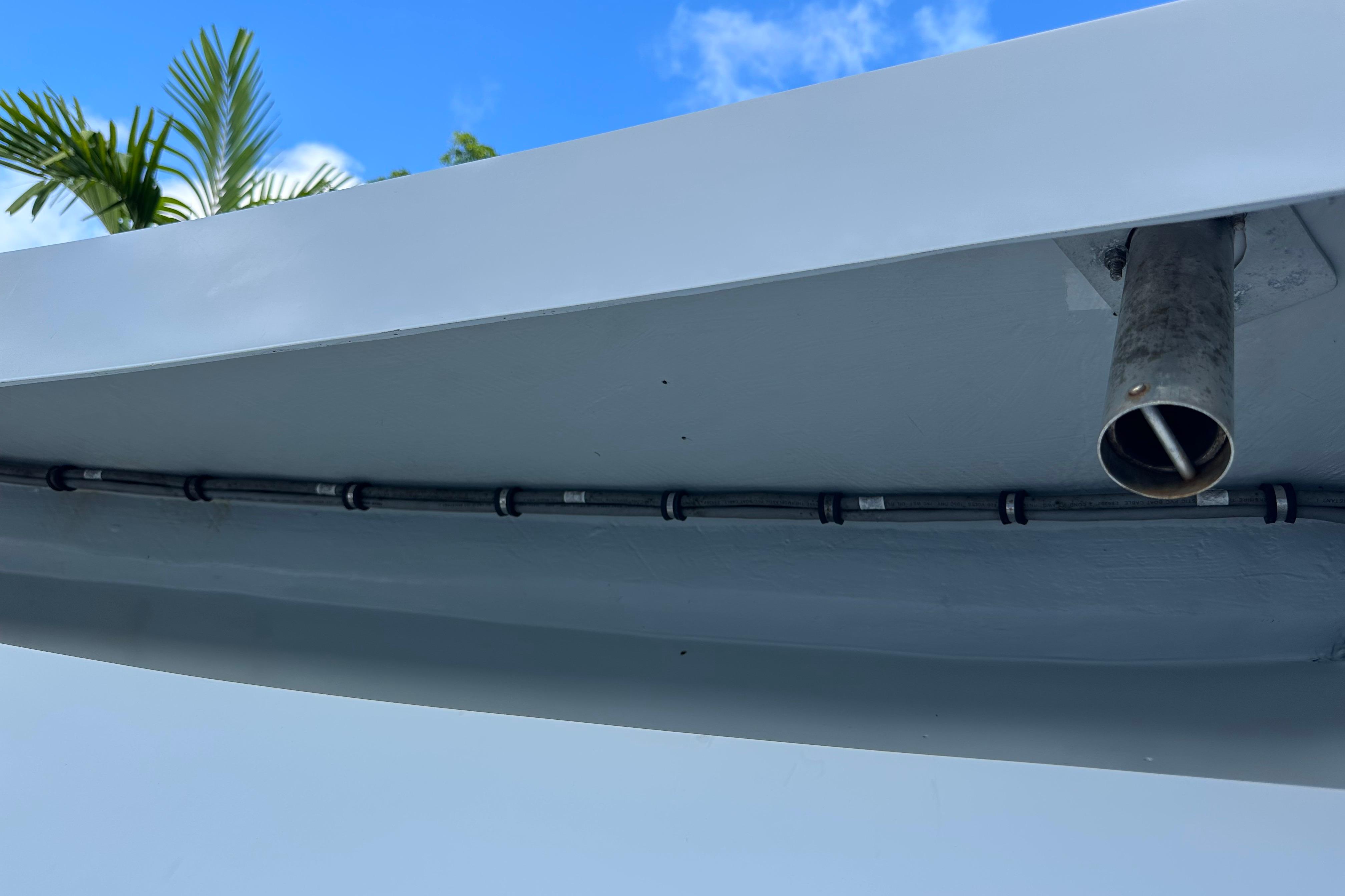2004 SeaVee Center Console boat underside with exhaust pipe and wiring, clear sky background.