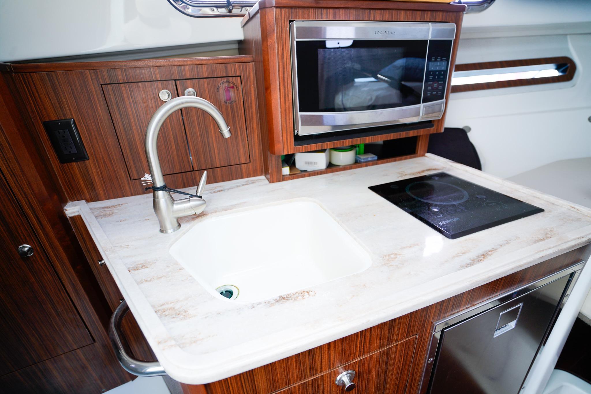 2020 Pursuit OS 325 Offshore yacht kitchen with sink, microwave, and stovetop.