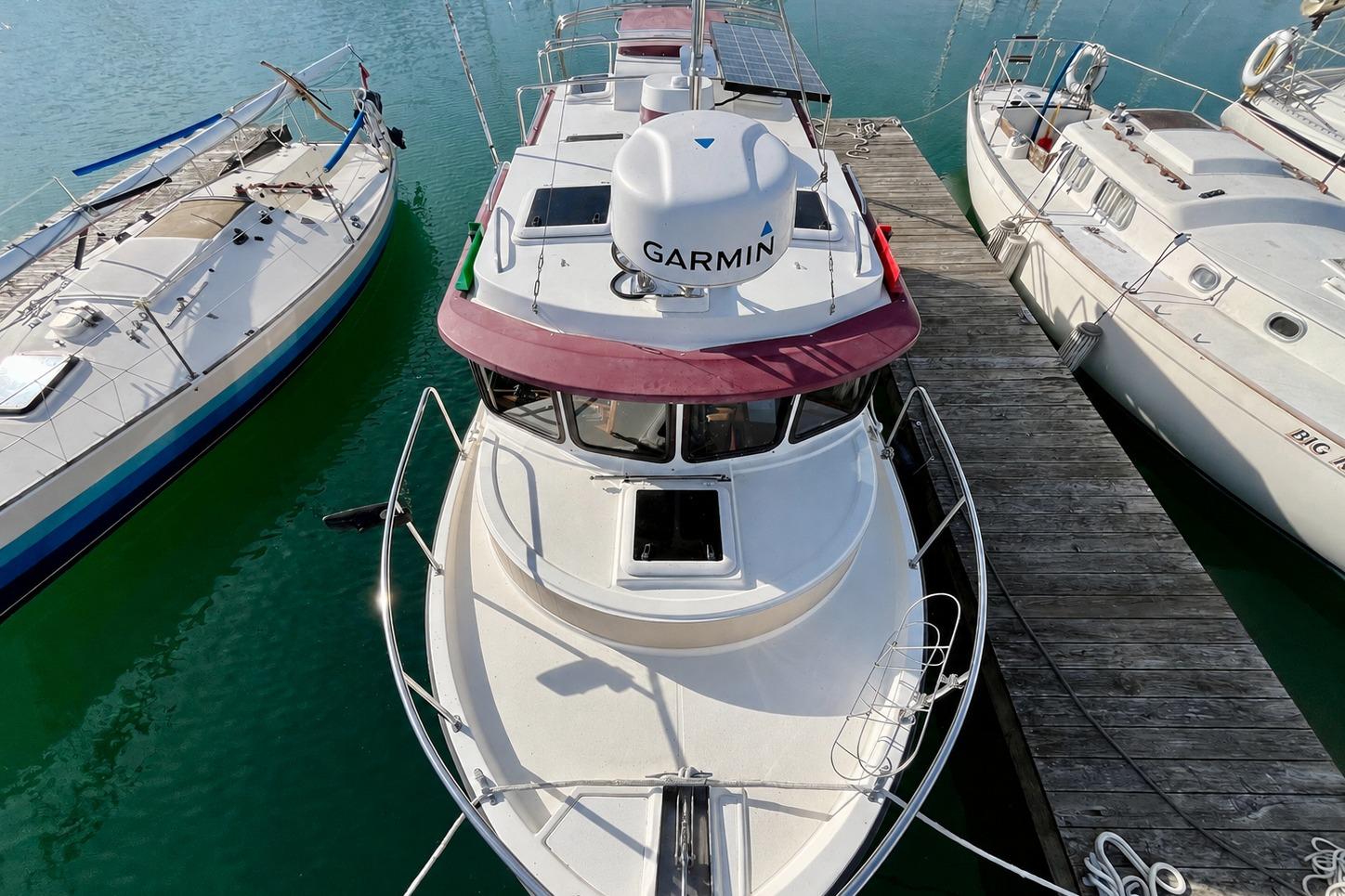 2013 Ranger Tugs R-27 boat docked between sailboats, featuring Garmin equipment.