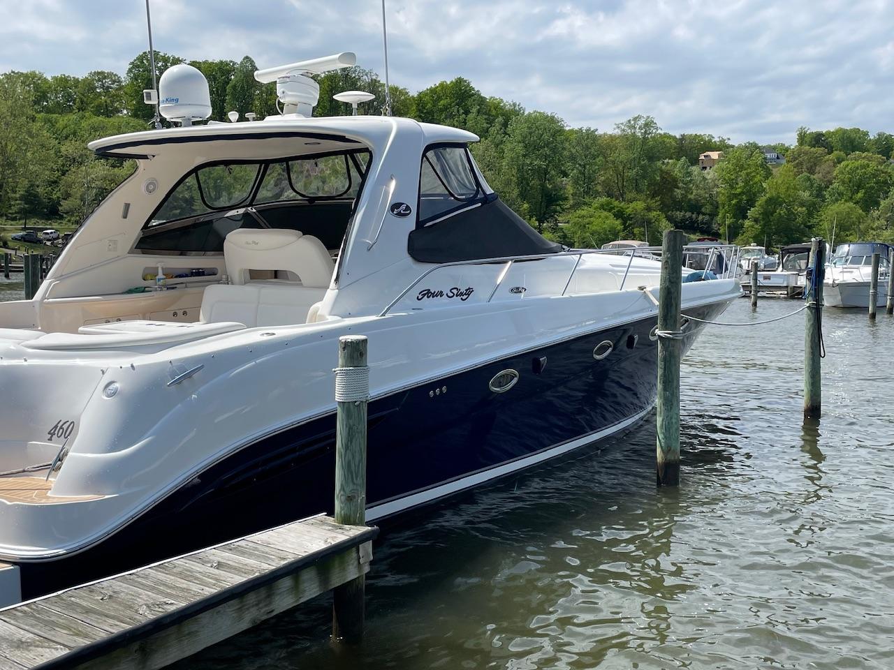 2004 Sea Ray 460 Sundancer yacht docked on a serene lake with lush greenery.