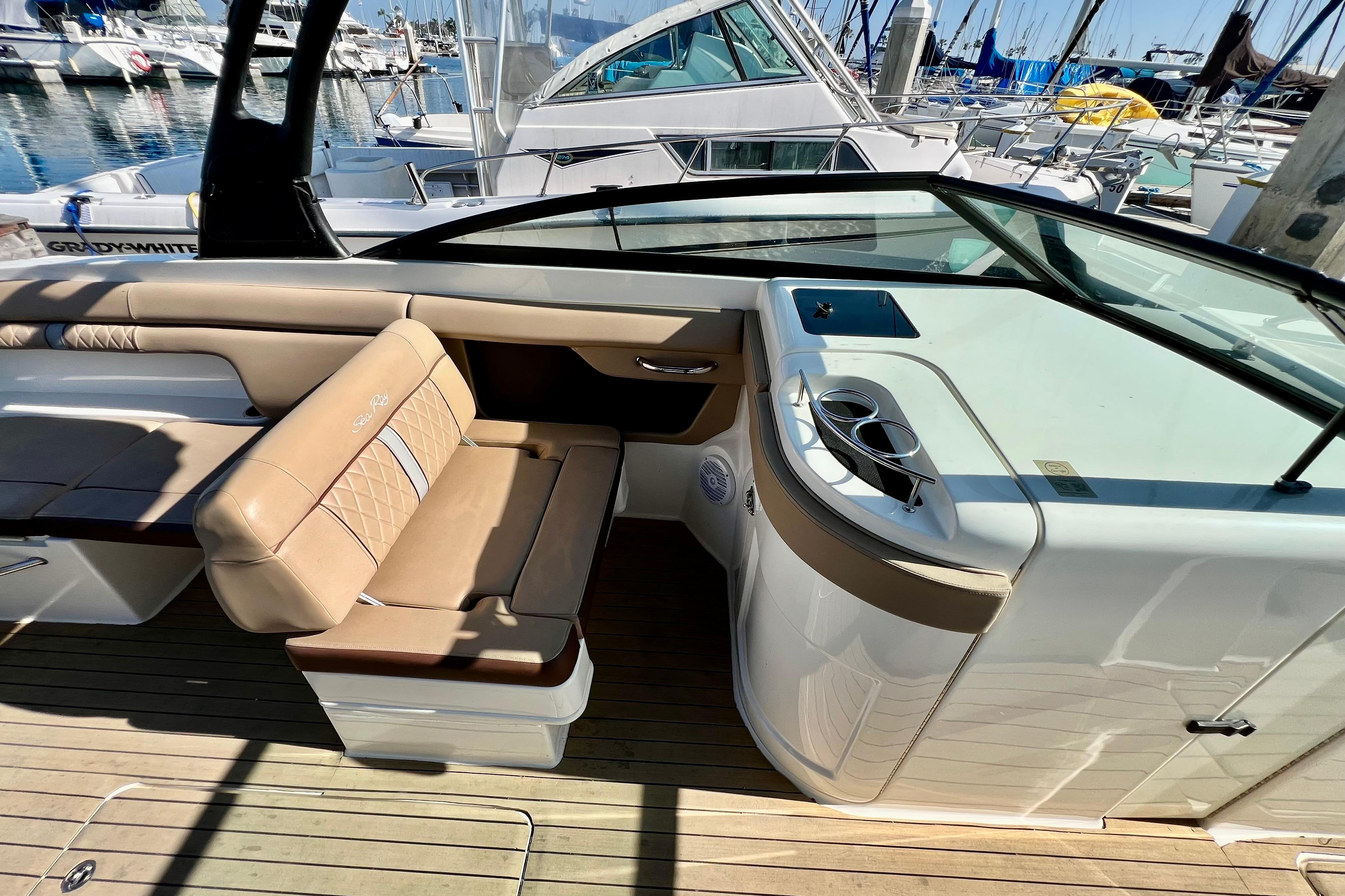 2016 Sea Ray 290 Sundeck Outboard interior with tan seating and cup holders at marina.
