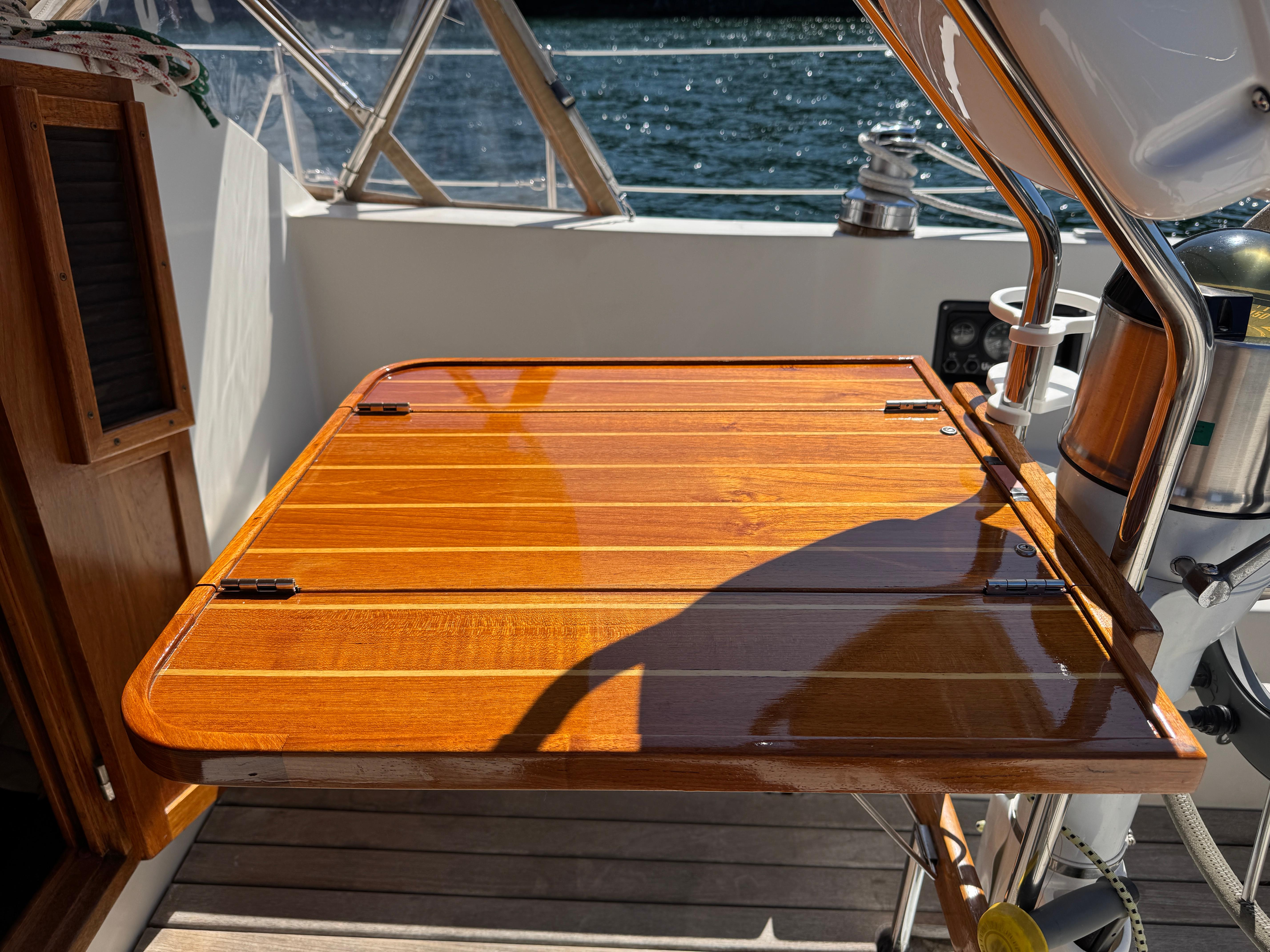 Polished wooden table on 1989 Nonsuch 30 Ultra sailboat deck, with ocean view.