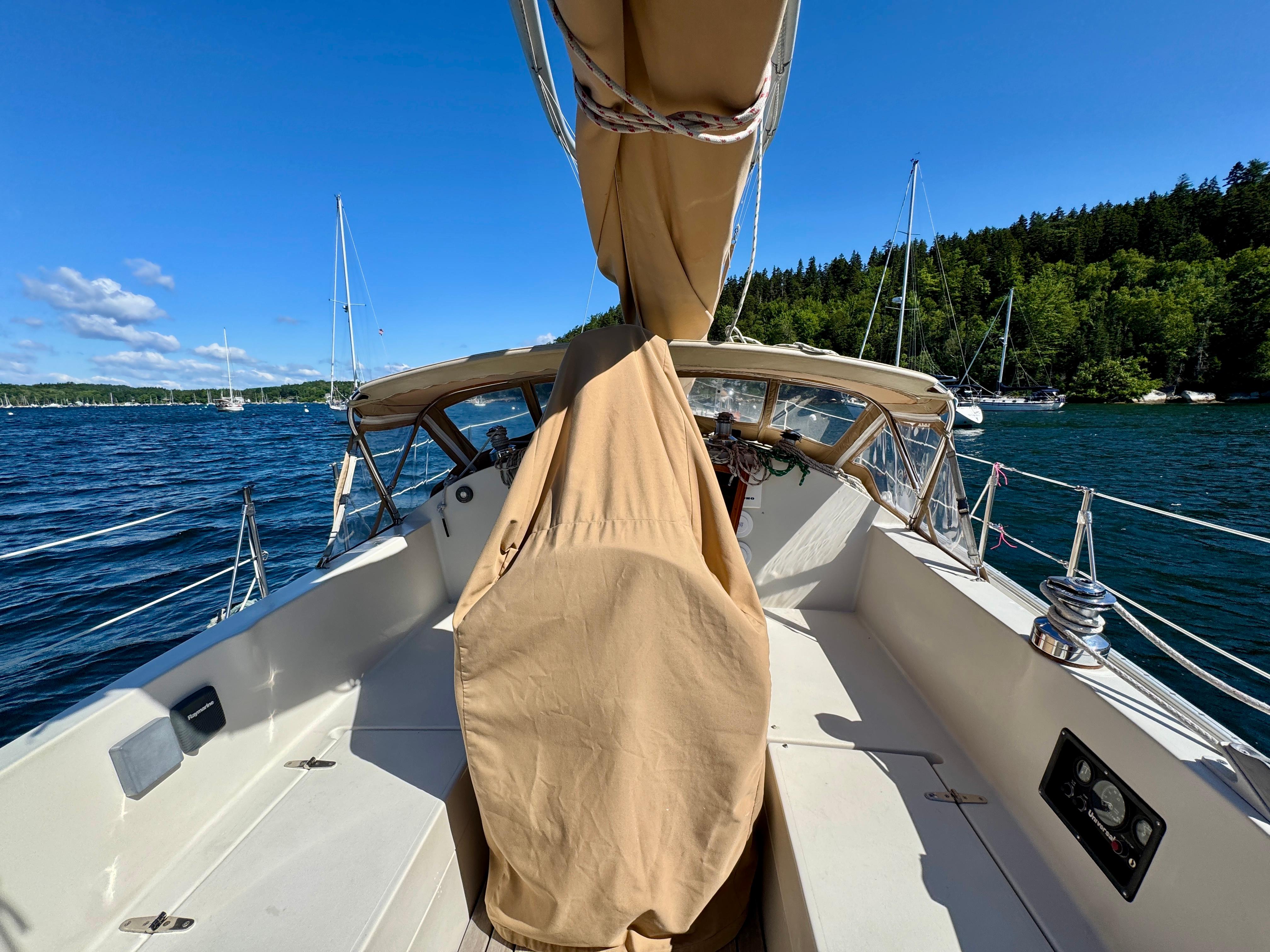 1989 Nonsuch 30 Ultra sailboat on a sunny day, surrounded by water and trees.