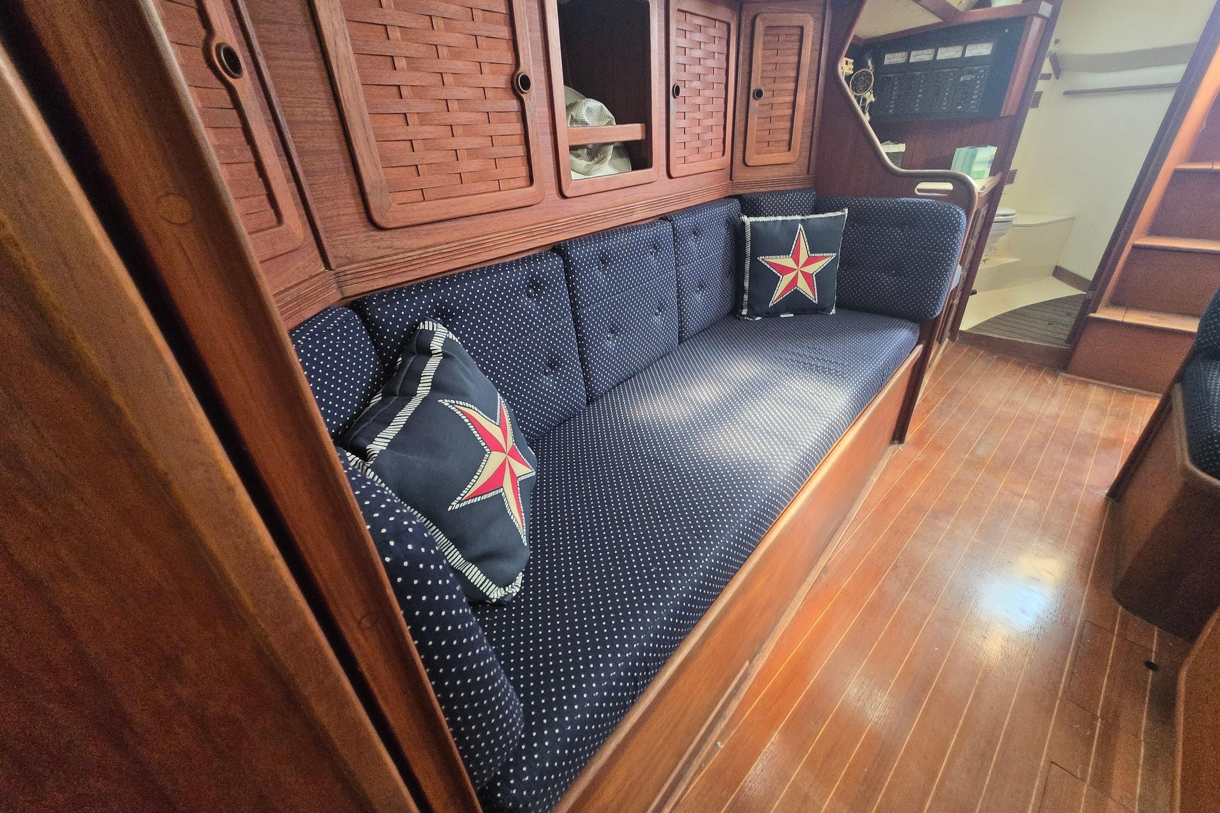 Interior of 1988 Sabre 38 sailboat with blue cushioned seating and star-patterned pillows.