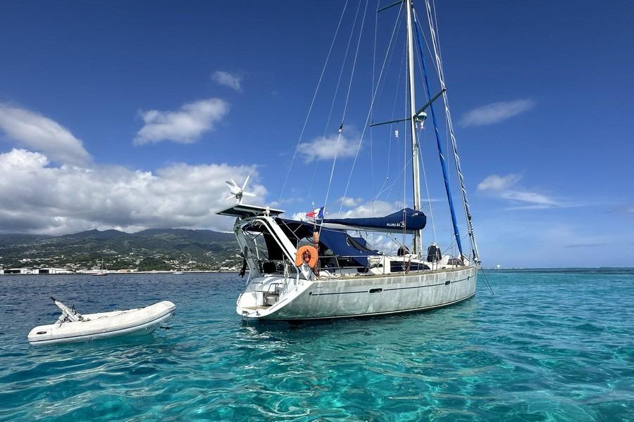 Sailing yacht Allures 44 (2010) anchored in clear blue waters with a small dinghy nearby.