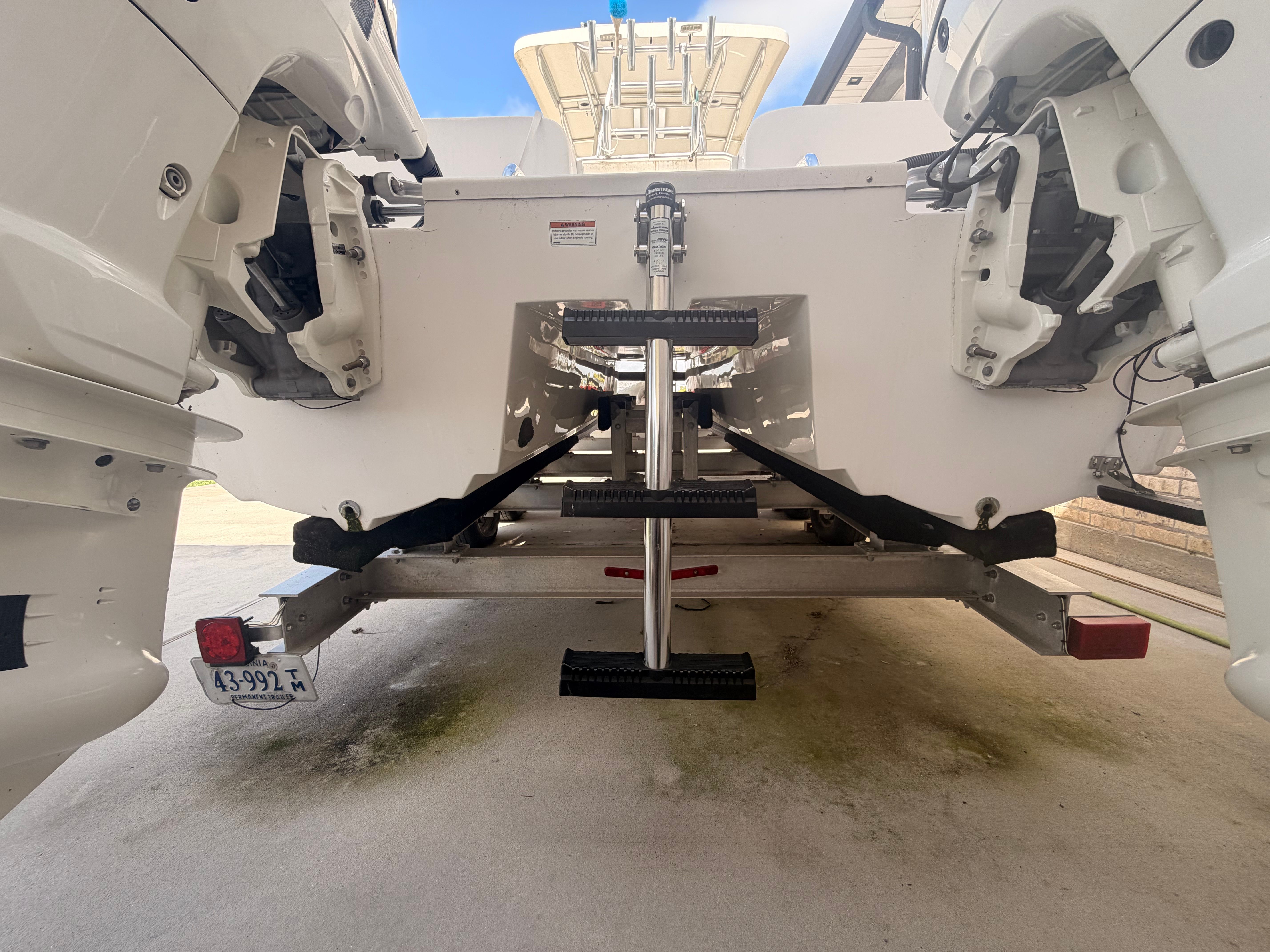 Rear view of a Twin Vee Ocean Cat boat on a trailer, featuring two engines and a ladder.