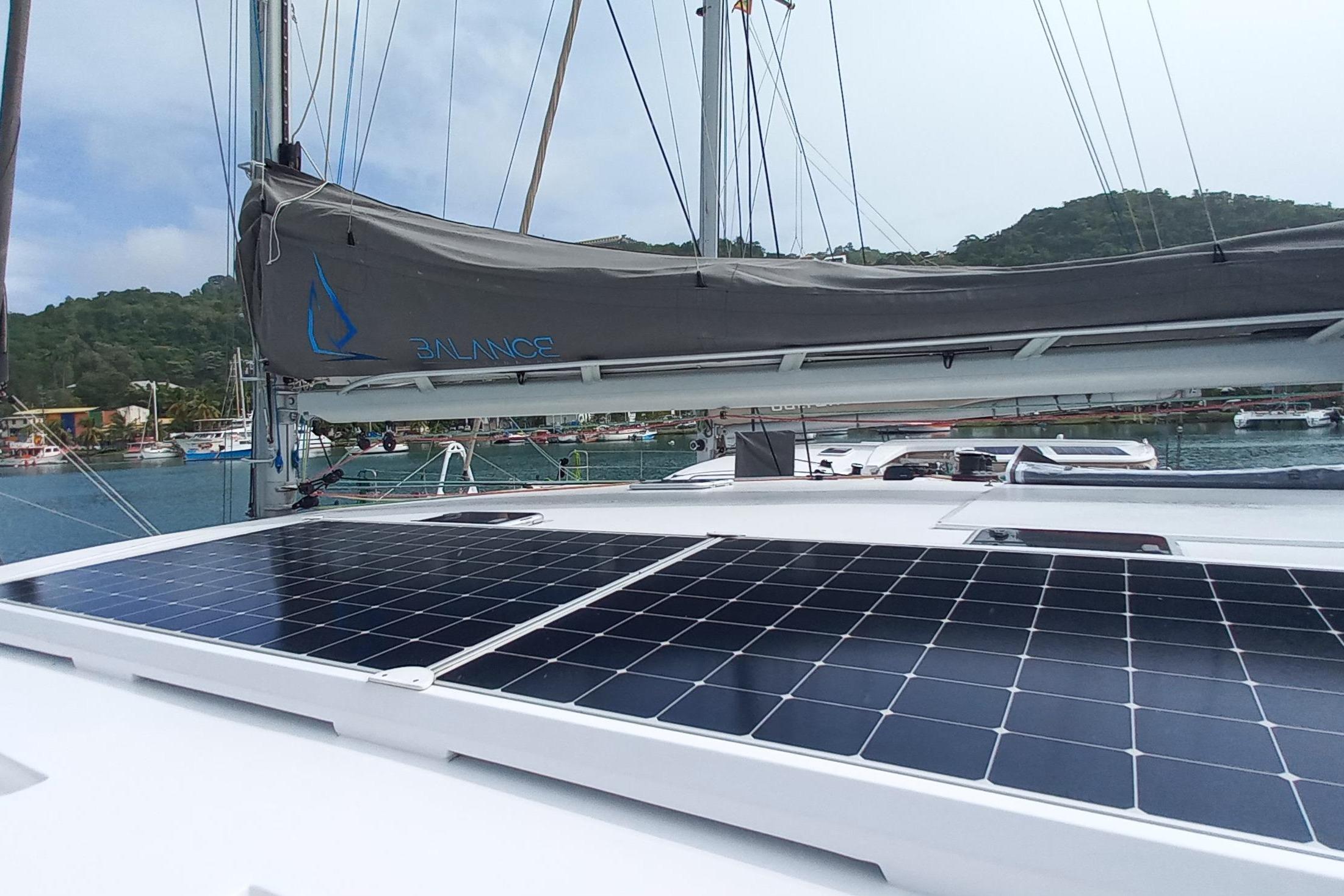 Sailboat Balance 482 (2022) with solar panels, docked in a scenic marina.