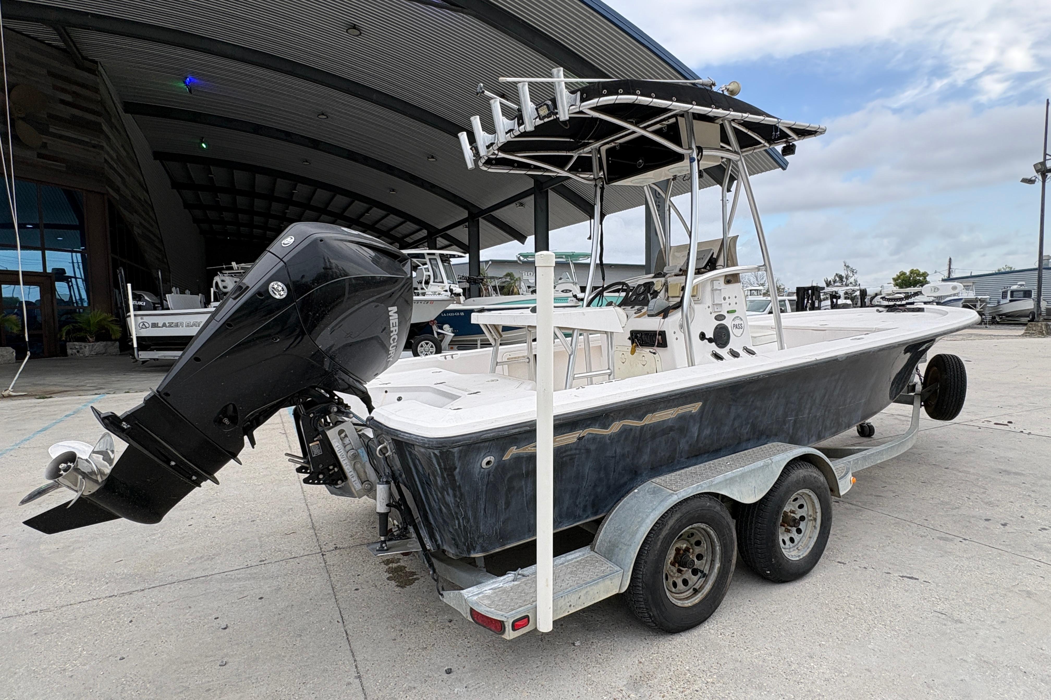 Kenner 21 VISION 2000 boat on trailer with outboard motor, parked outdoors.