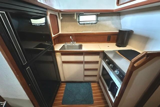 Compact kitchen in 1989 Carver 32 Aft Cabin Motor Yacht with sink, stove, and fridge.
