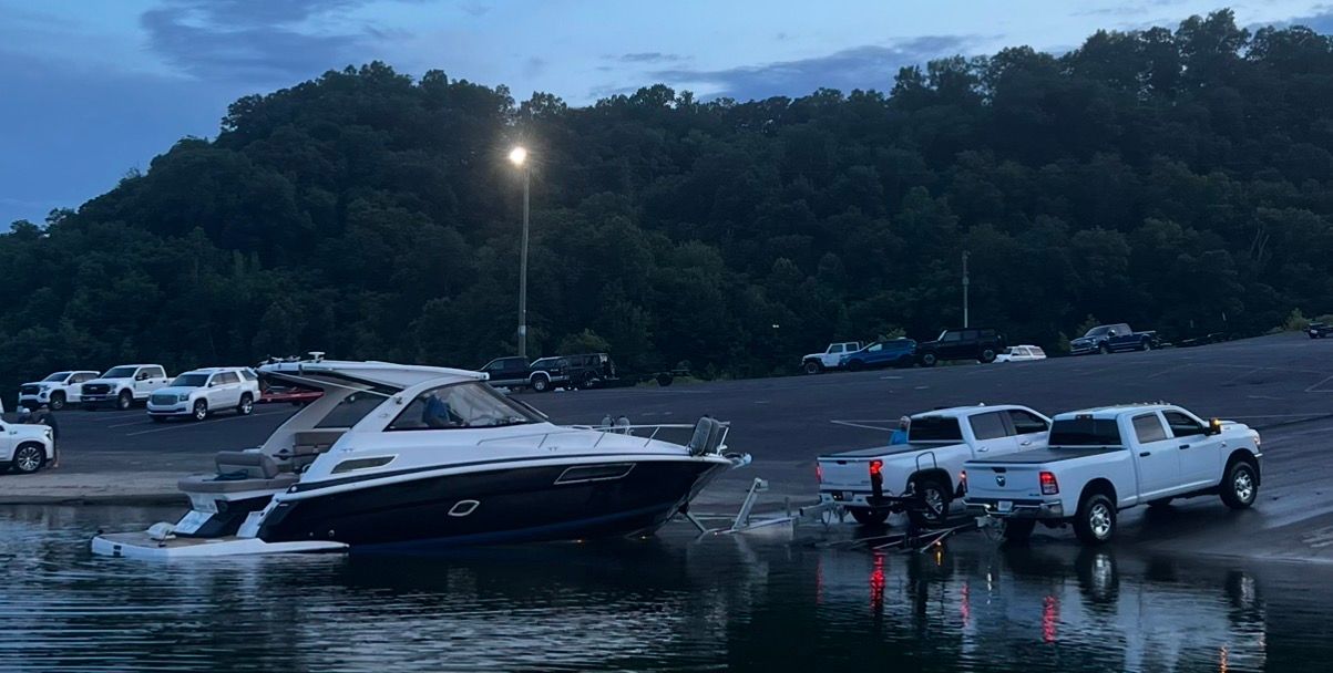 2015 Regal 35 Sport Coupe at boat ramp with trucks.