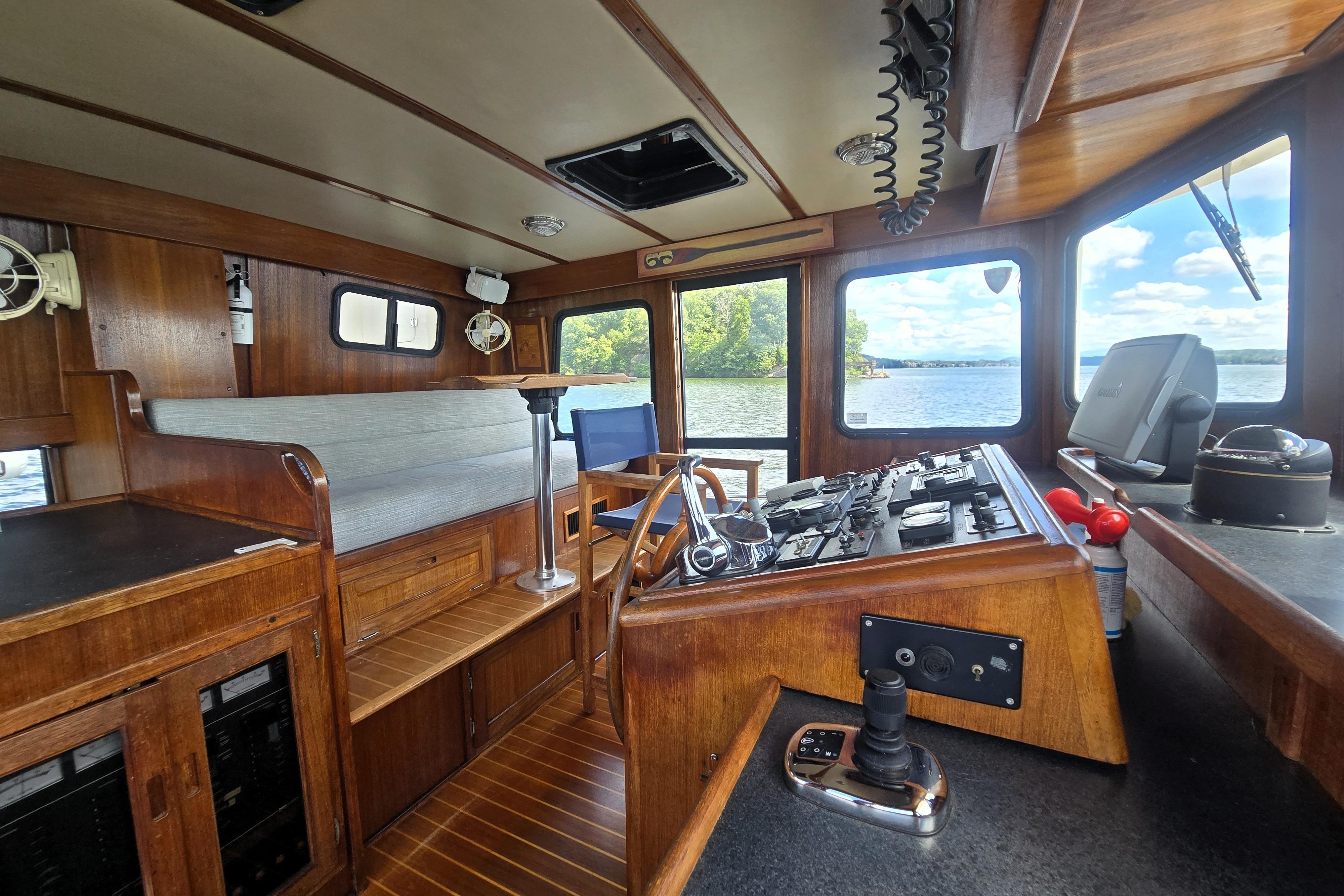 Interior of 2000 Nordic Tug 42 Flybridge with wooden helm and scenic water view.