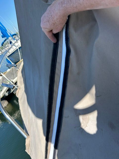 Close-up of a boat cover with a zipper, held by a hand.