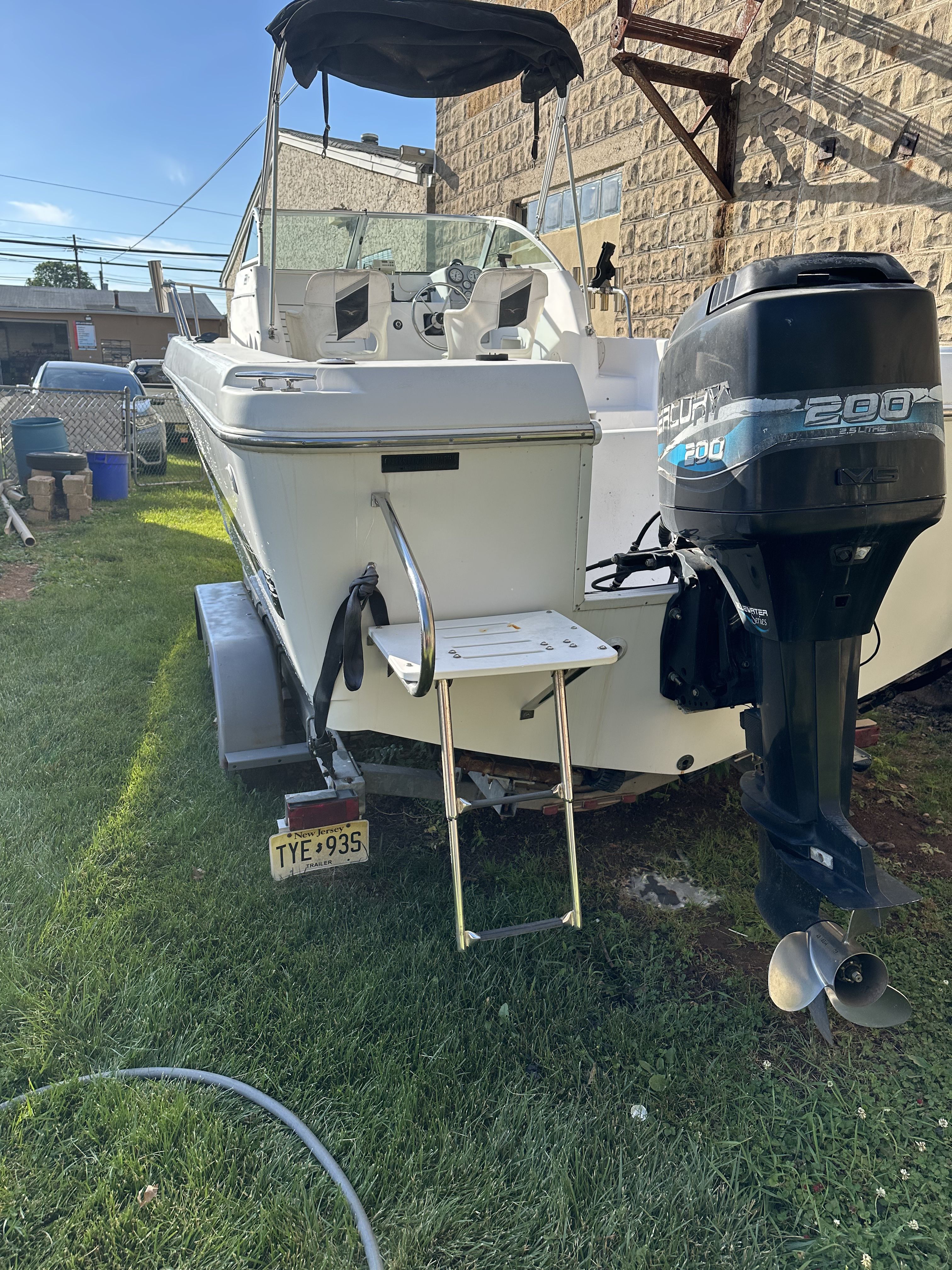 A 1999 Pro-Line 221 boat is on a trailer outdoors.